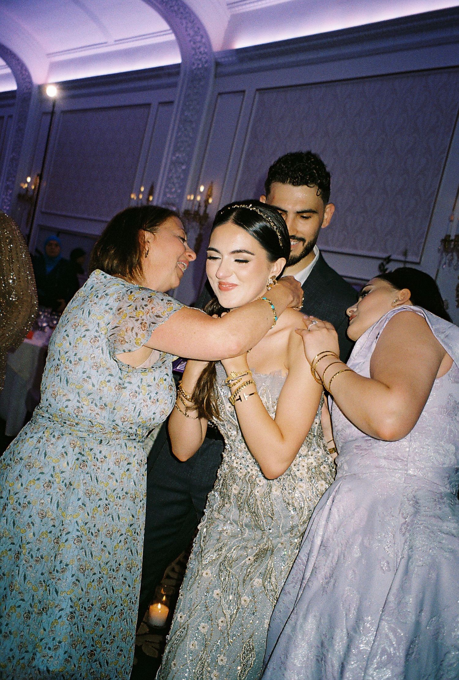 Guests dancing and celebrating at an elegant indoor party with purple lighting.