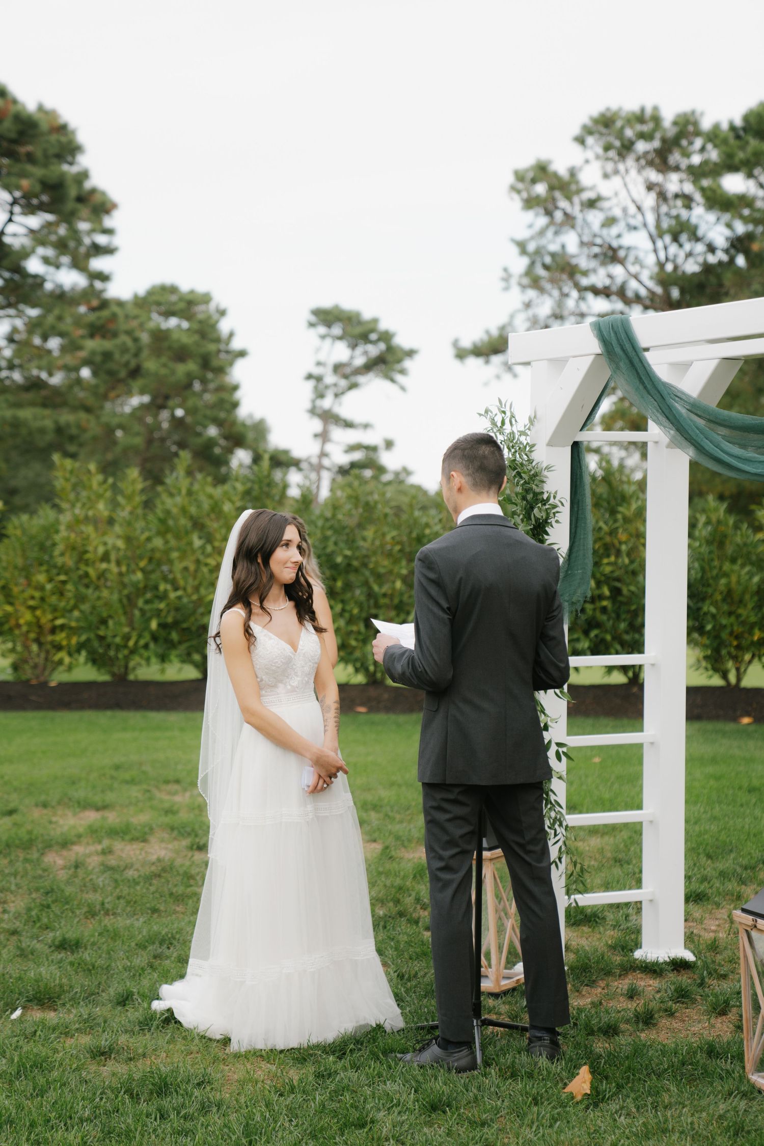 A couple shares a private first look moment before their wedding ceremony on a grassy lawn with white pillars.