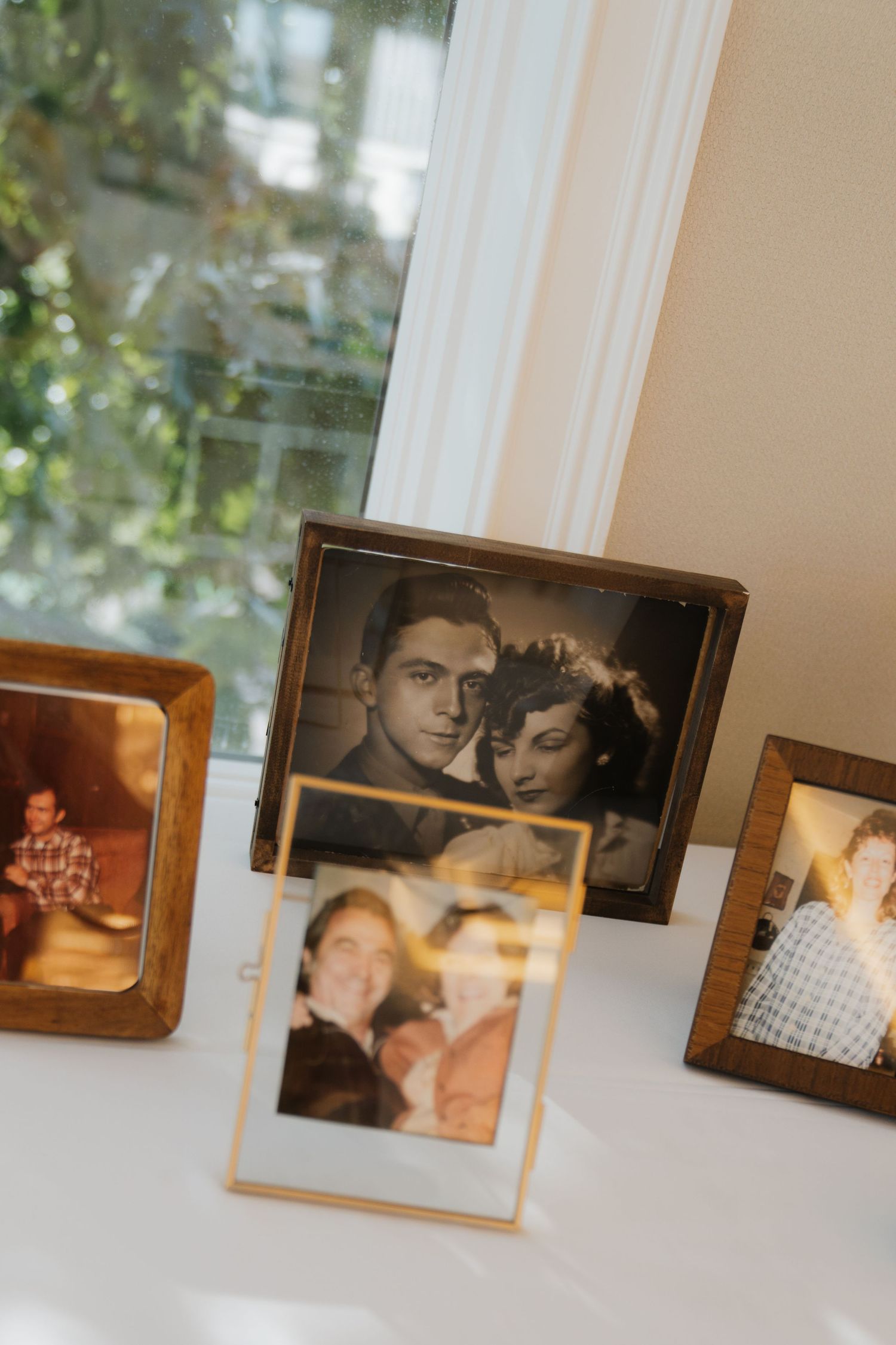 A series of vintage black and white photographs displayed in frames on a white wall near a window.