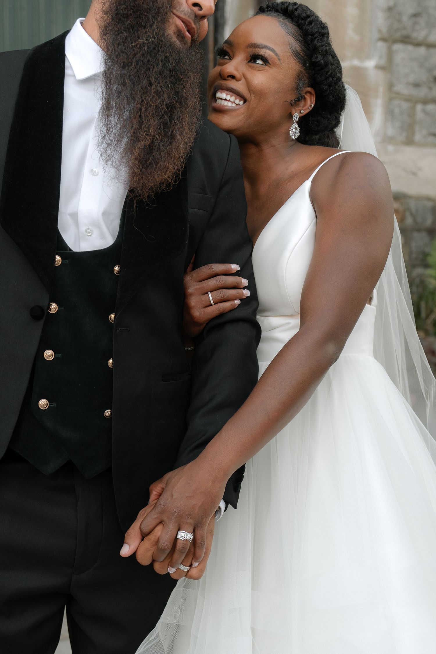 A tender wedding moment captured in close-up showing details of a white bridal gown.