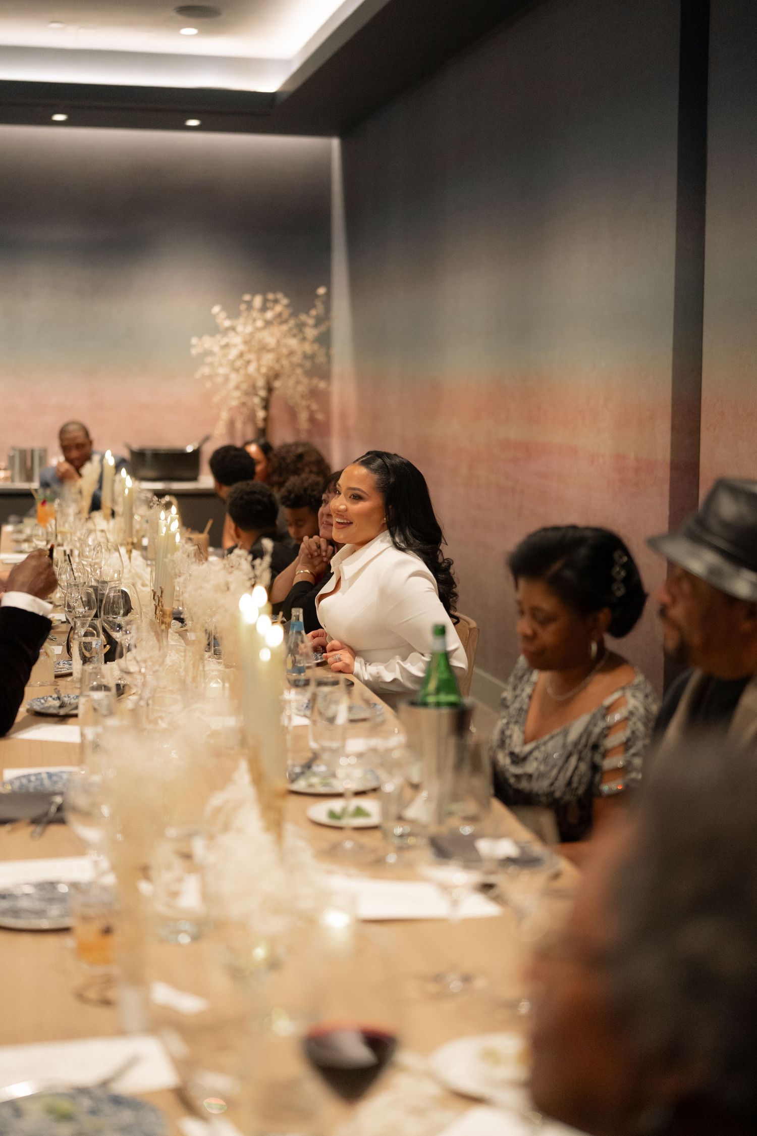 Guests seated at an elegant dinner party with wine glasses and table decorations.