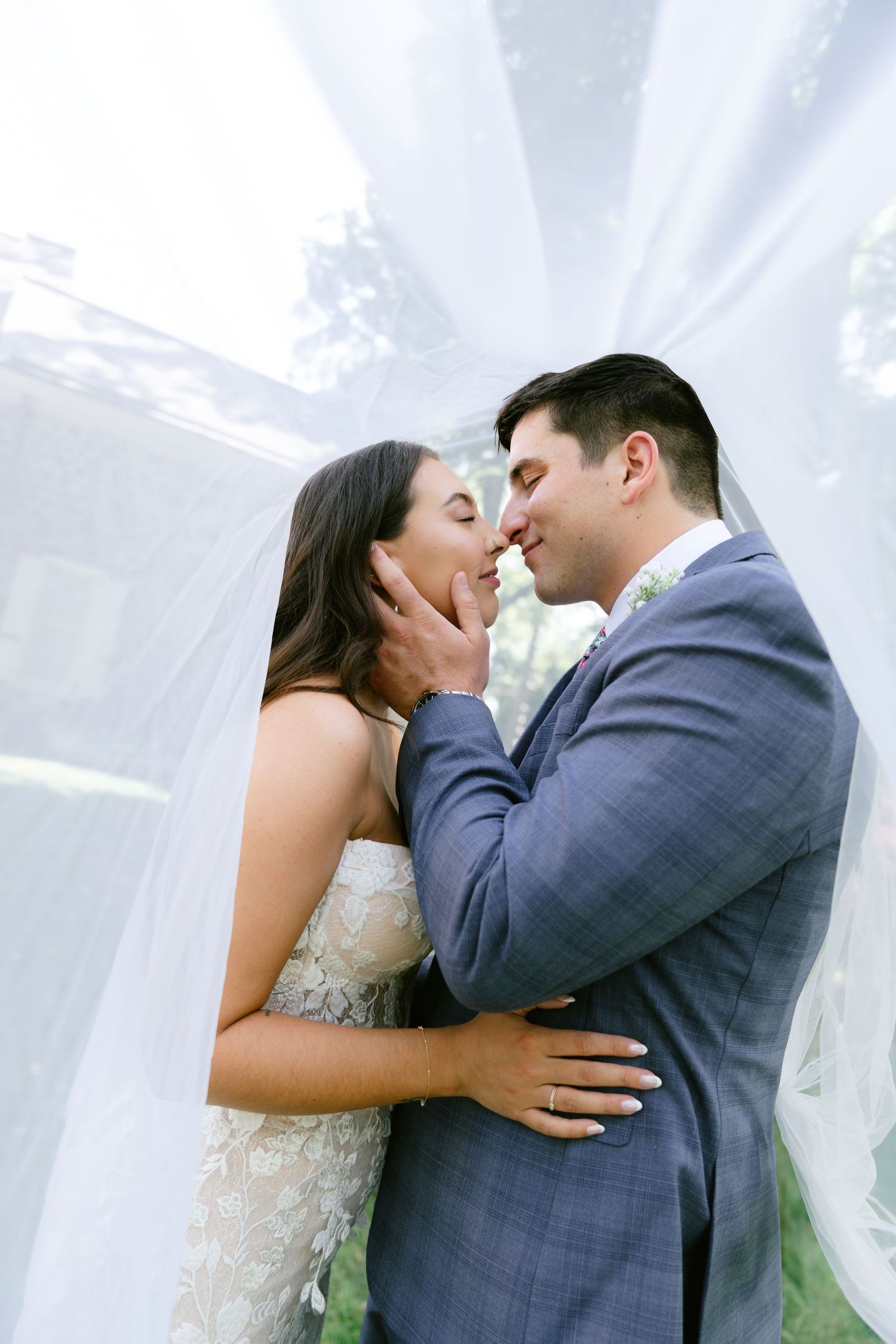 A romantic wedding couple shares intimate kisses against a white backdrop.