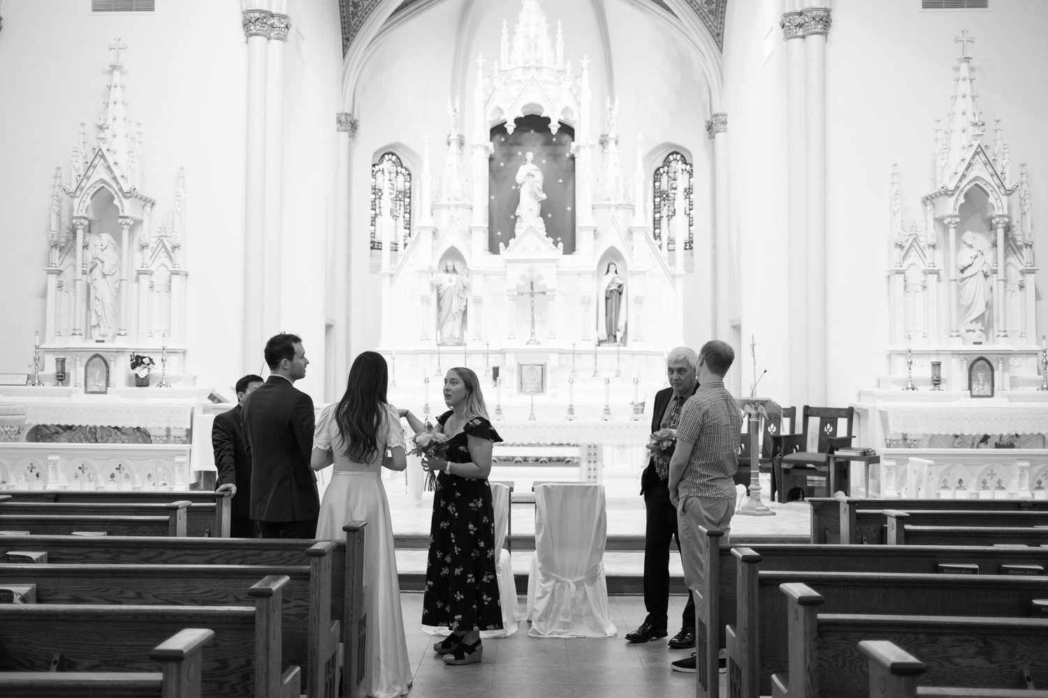 Black and white photo of a small wedding ceremony in a beautiful church sanctuary.