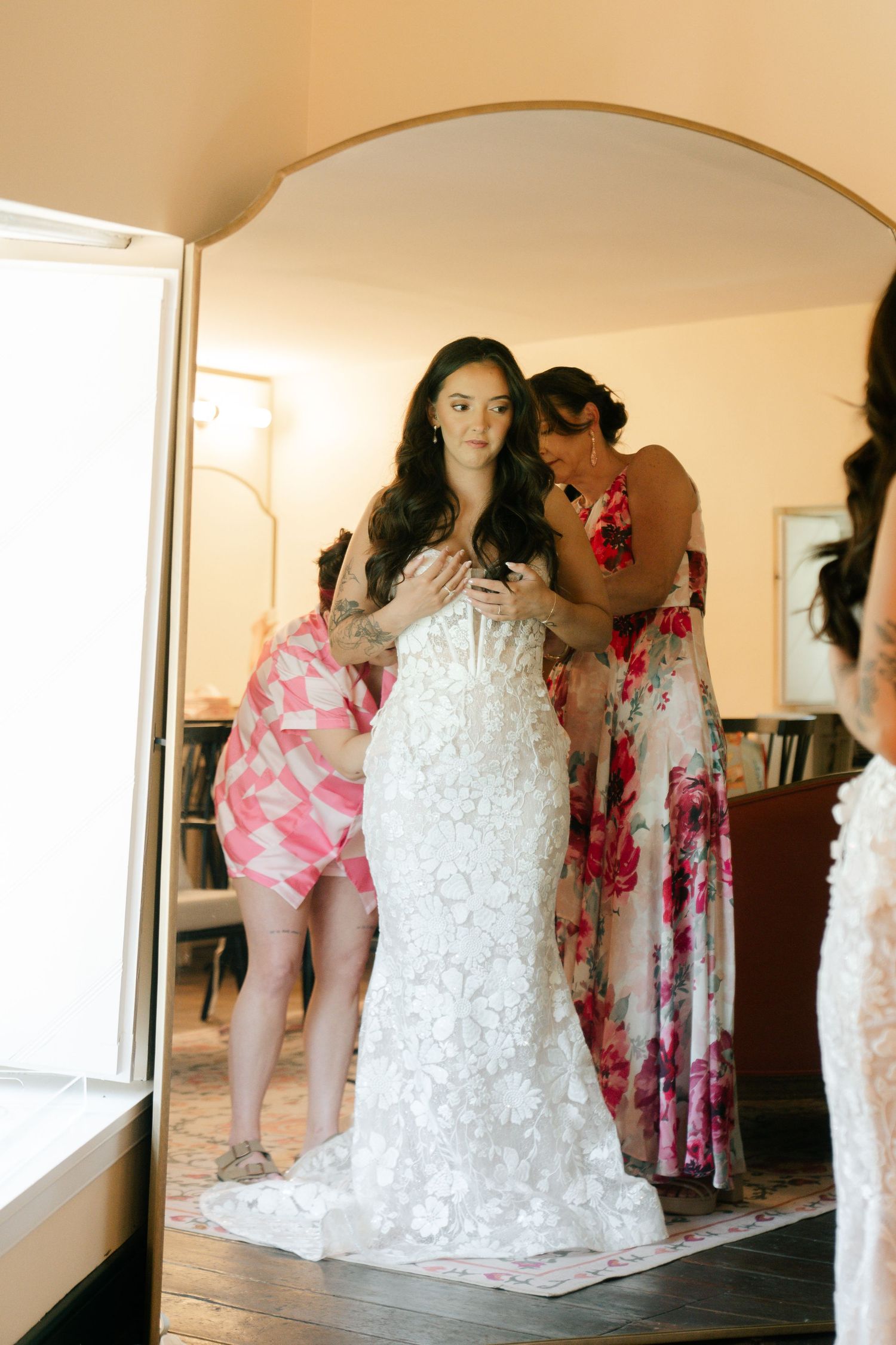 Wedding preparations with bridesmaids in floral dresses and bride in white lace gown.