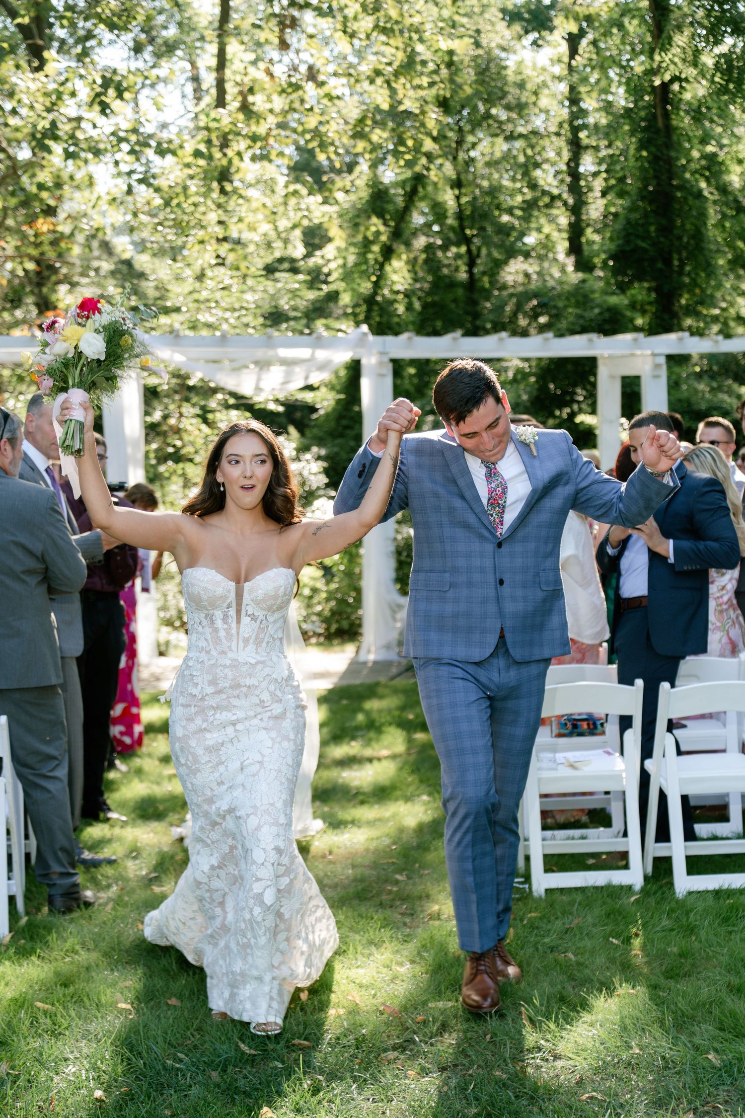 Joyful wedding recessional on a sunny garden path.