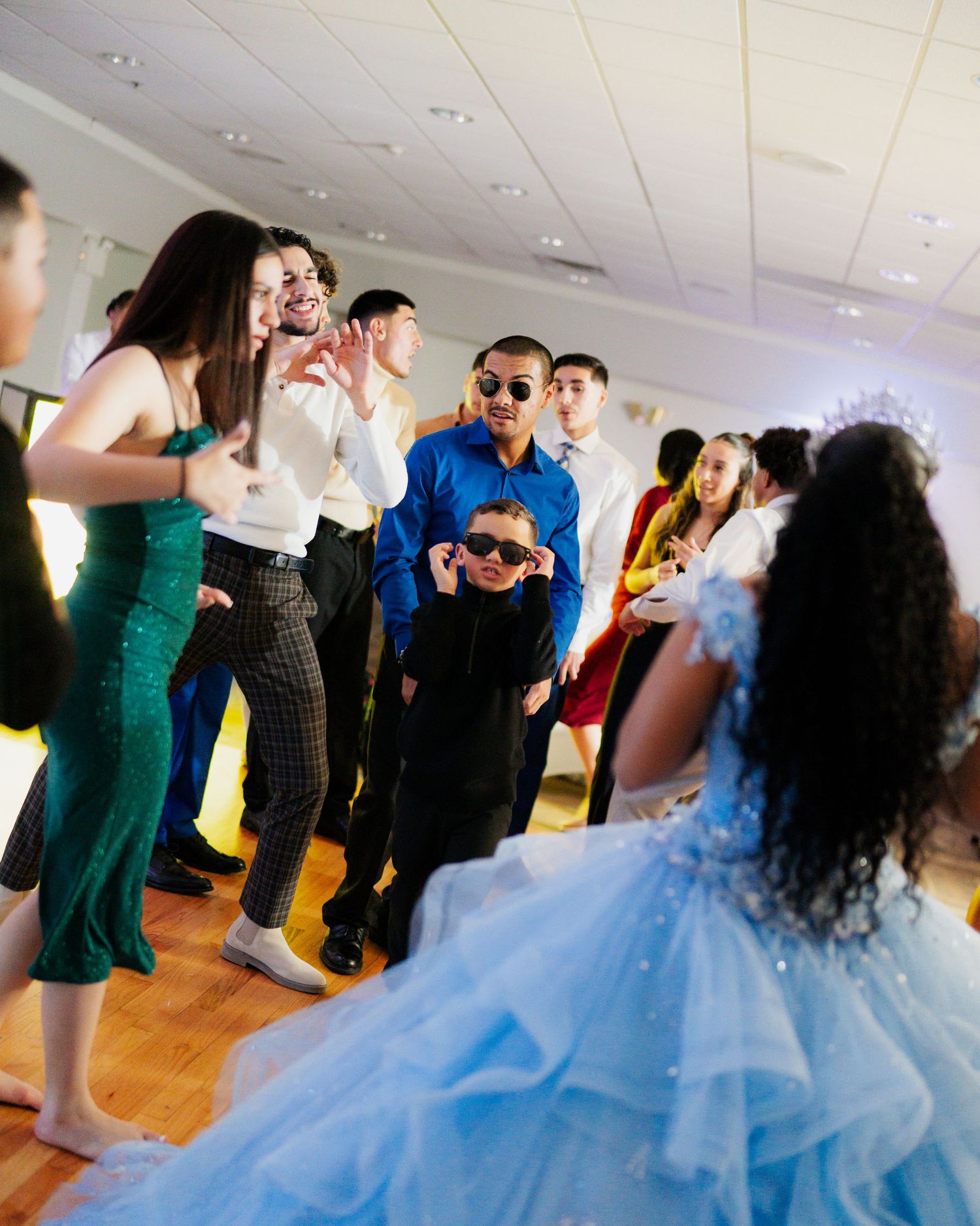 Party guests dancing and celebrating at an event with a light blue ballgown as the centerpiece.