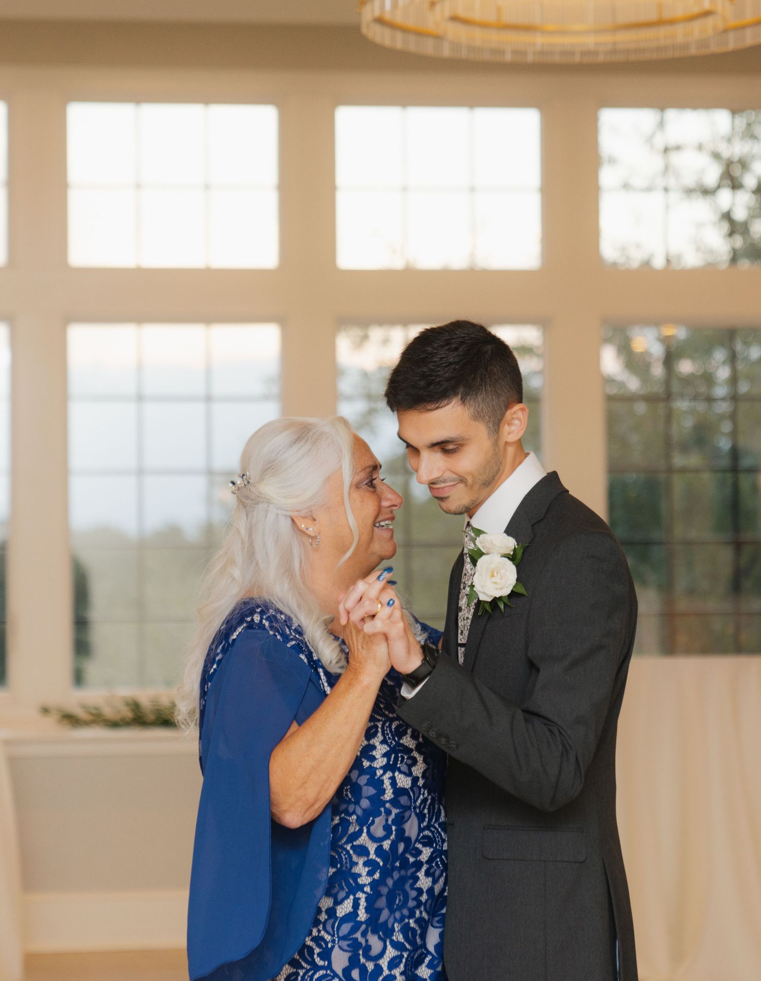 A tender moment between a couple dancing in a sunlit room with large windows.
