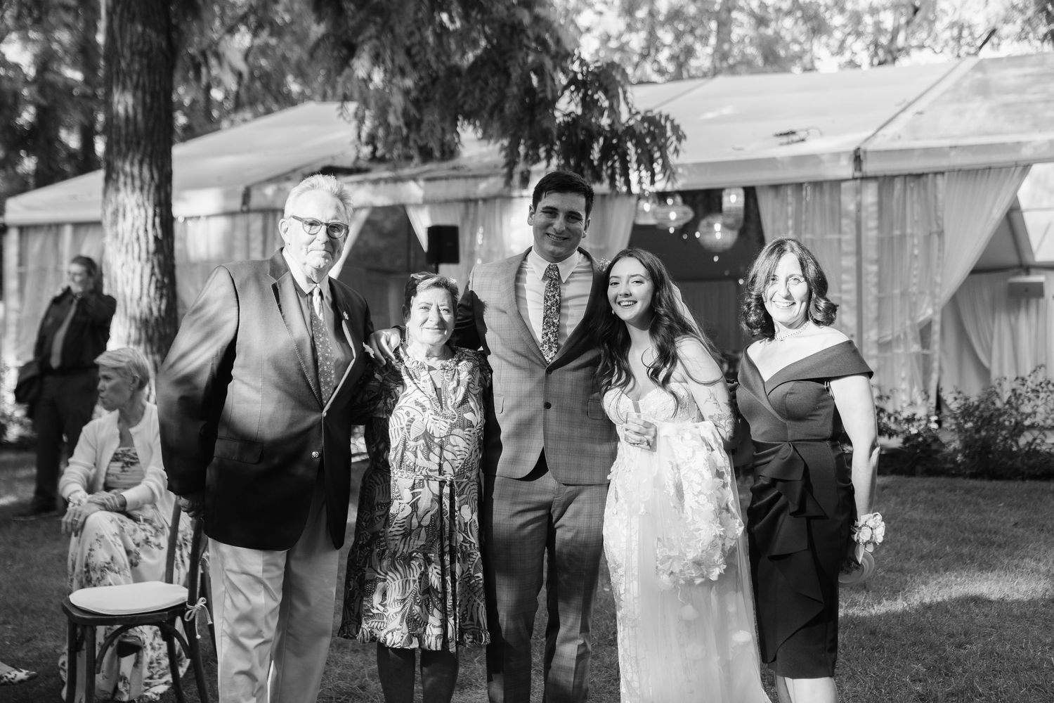 Wedding guests gather for black and white photos outside a venue.