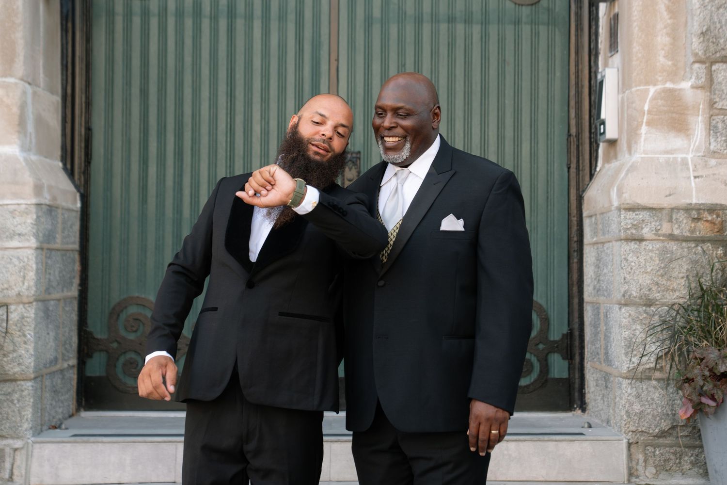 Two people in formal attire share joyful moment outside church entrance.