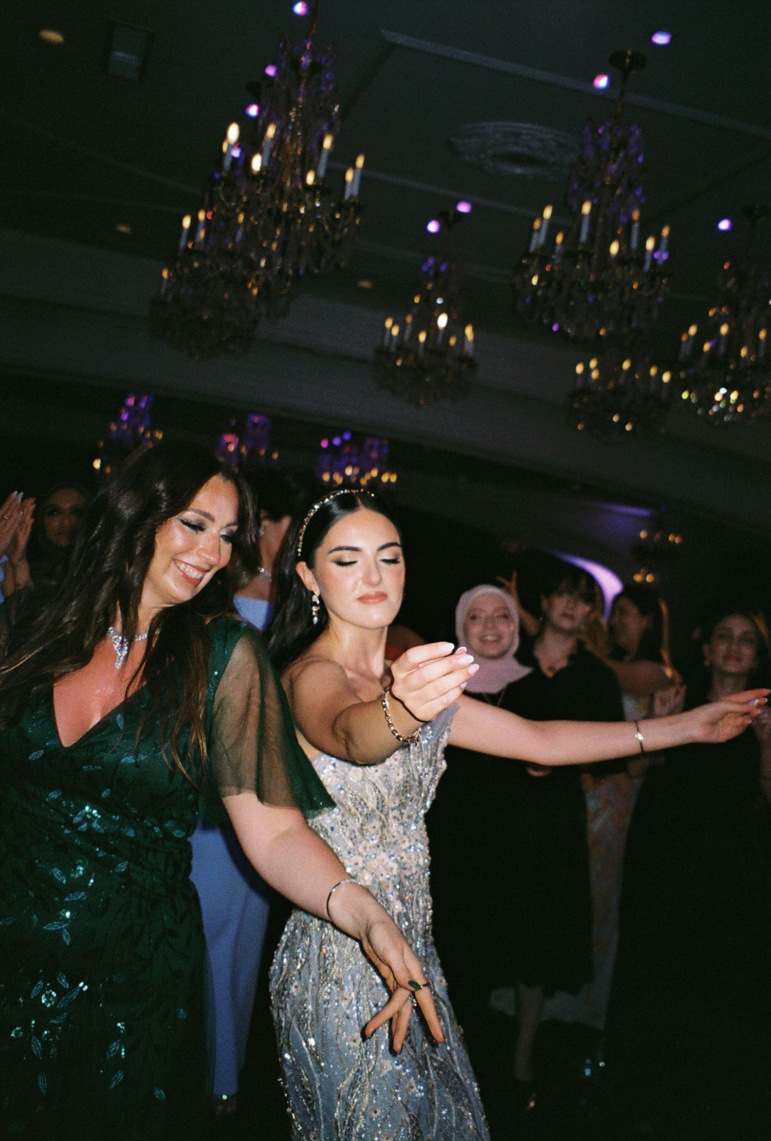Wedding reception dance floor with sparkling chandelier lighting and festive atmosphere.