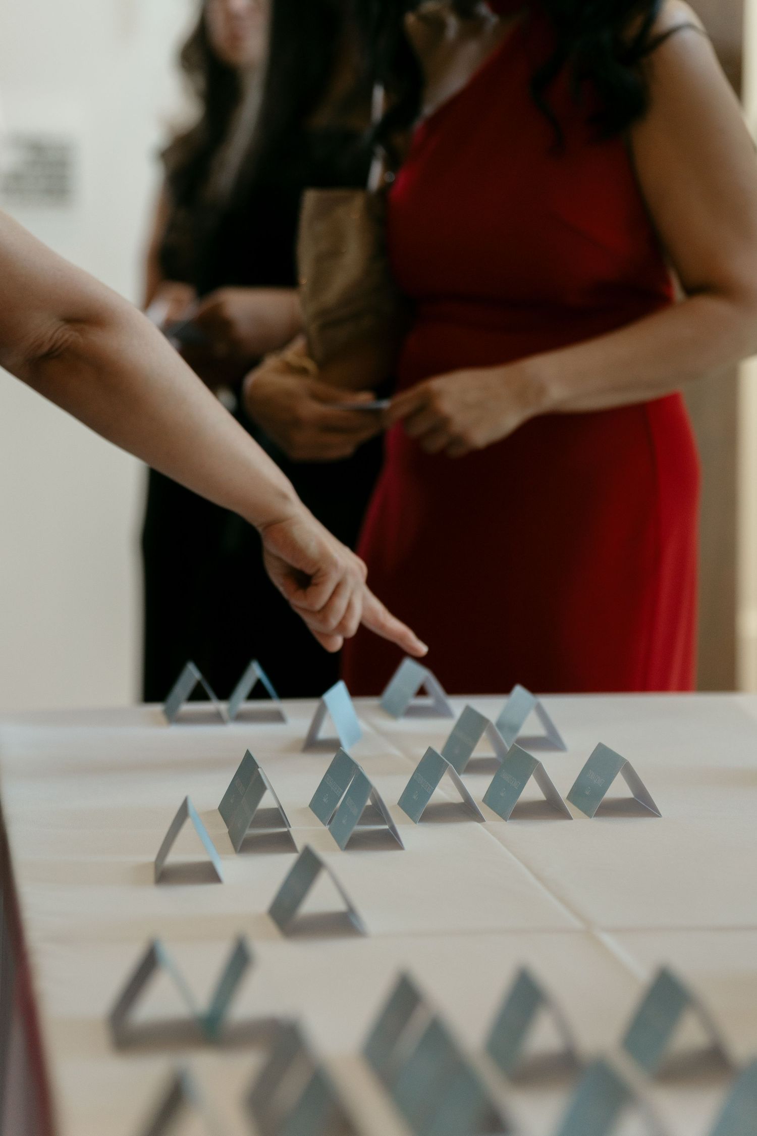 Guest points at triangular mirrored place card holders arranged on table at wedding reception.
