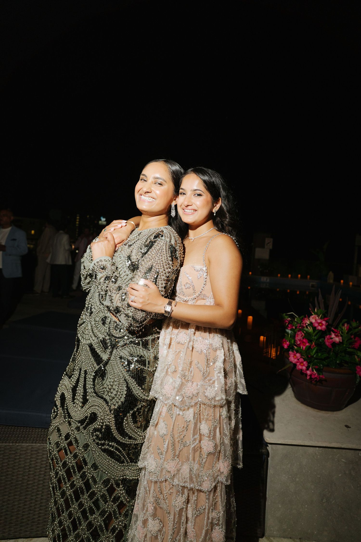 Guests in festive dresses enjoy an evening celebration outdoors.