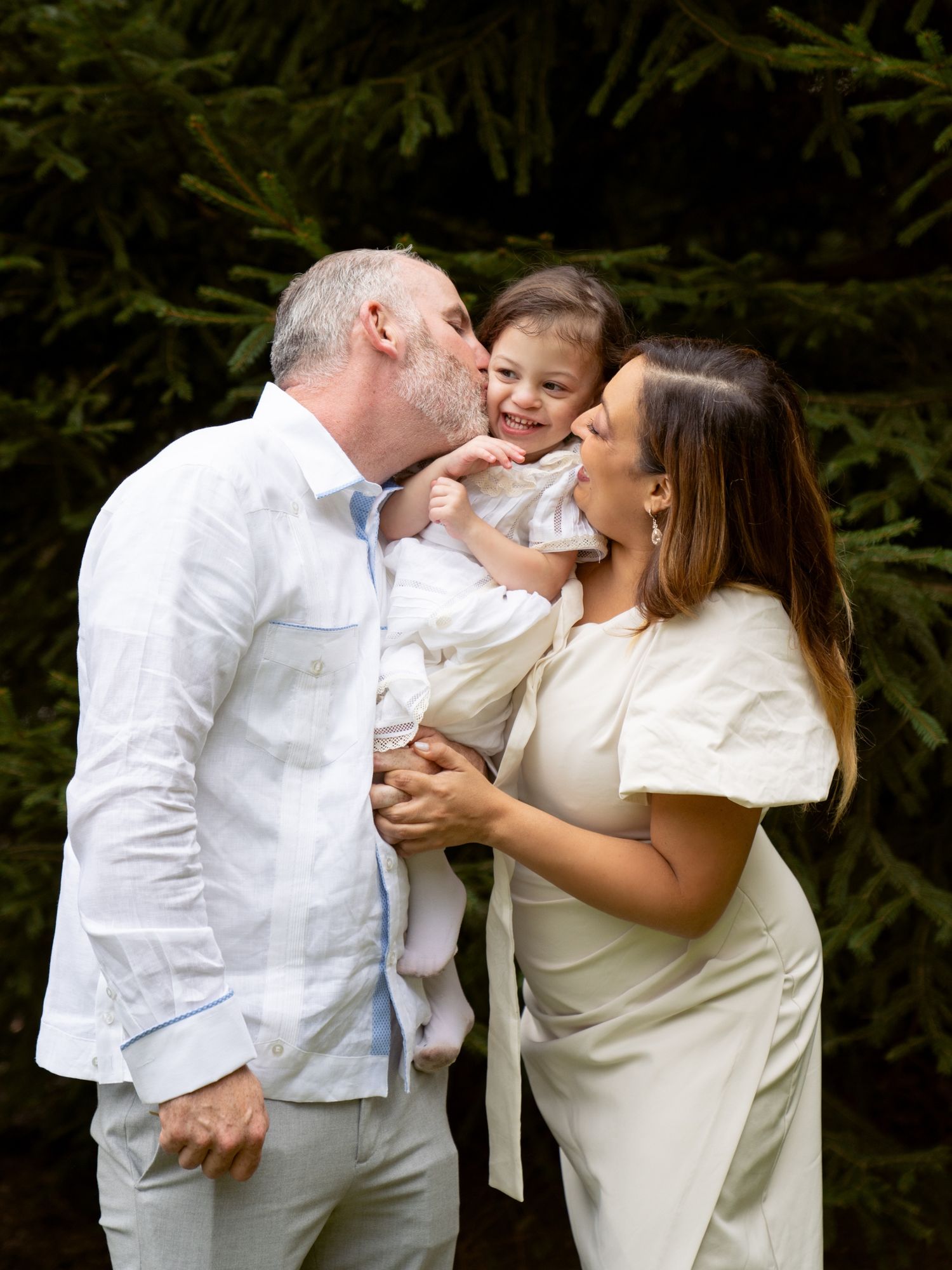 Joyful outdoor photoshoot with people in white attire sharing candid laughing moments.