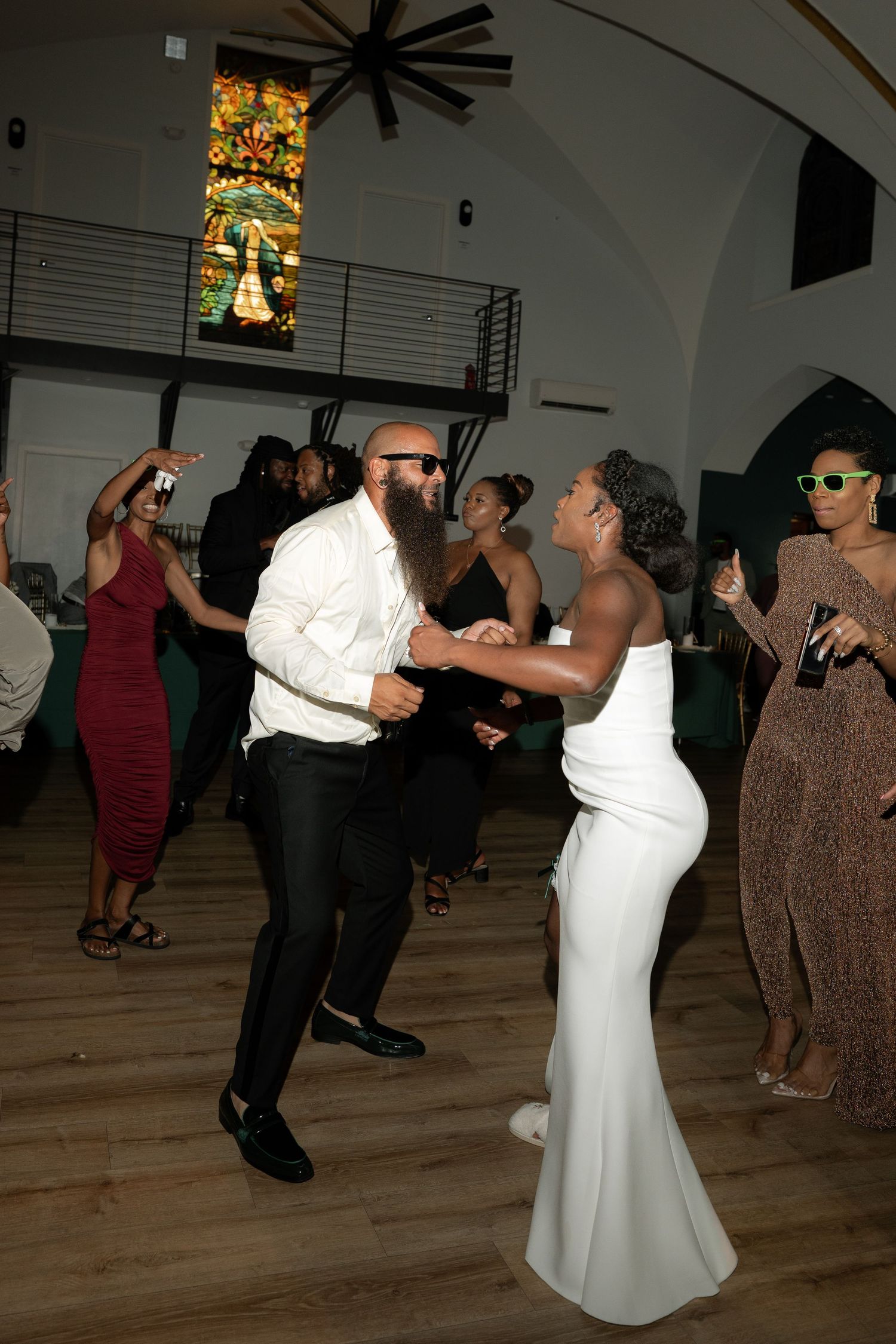 Wedding reception dance floor filled with guests enjoying themselves under decorative lighting.