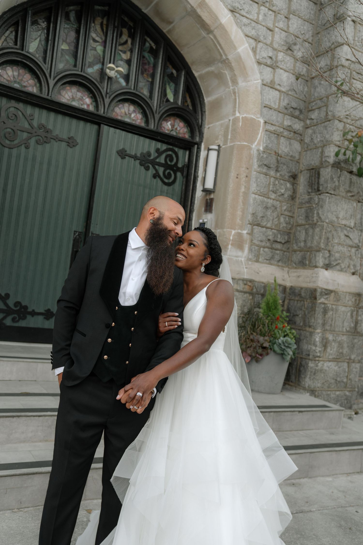 A romantic wedding photoshoot in front of a stone church with elegant archways.