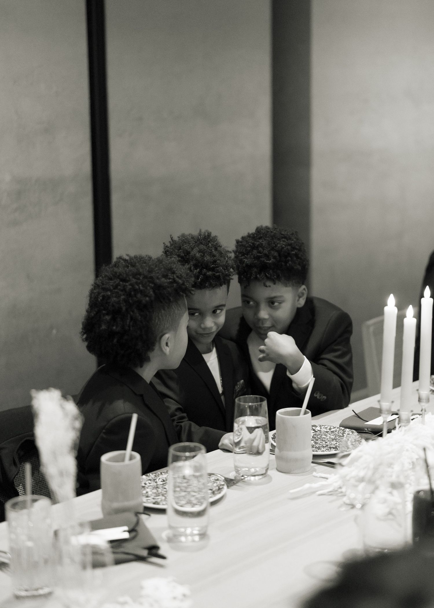 Guests seated at a formal dinner table with glowing white candles creating an intimate atmosphere.