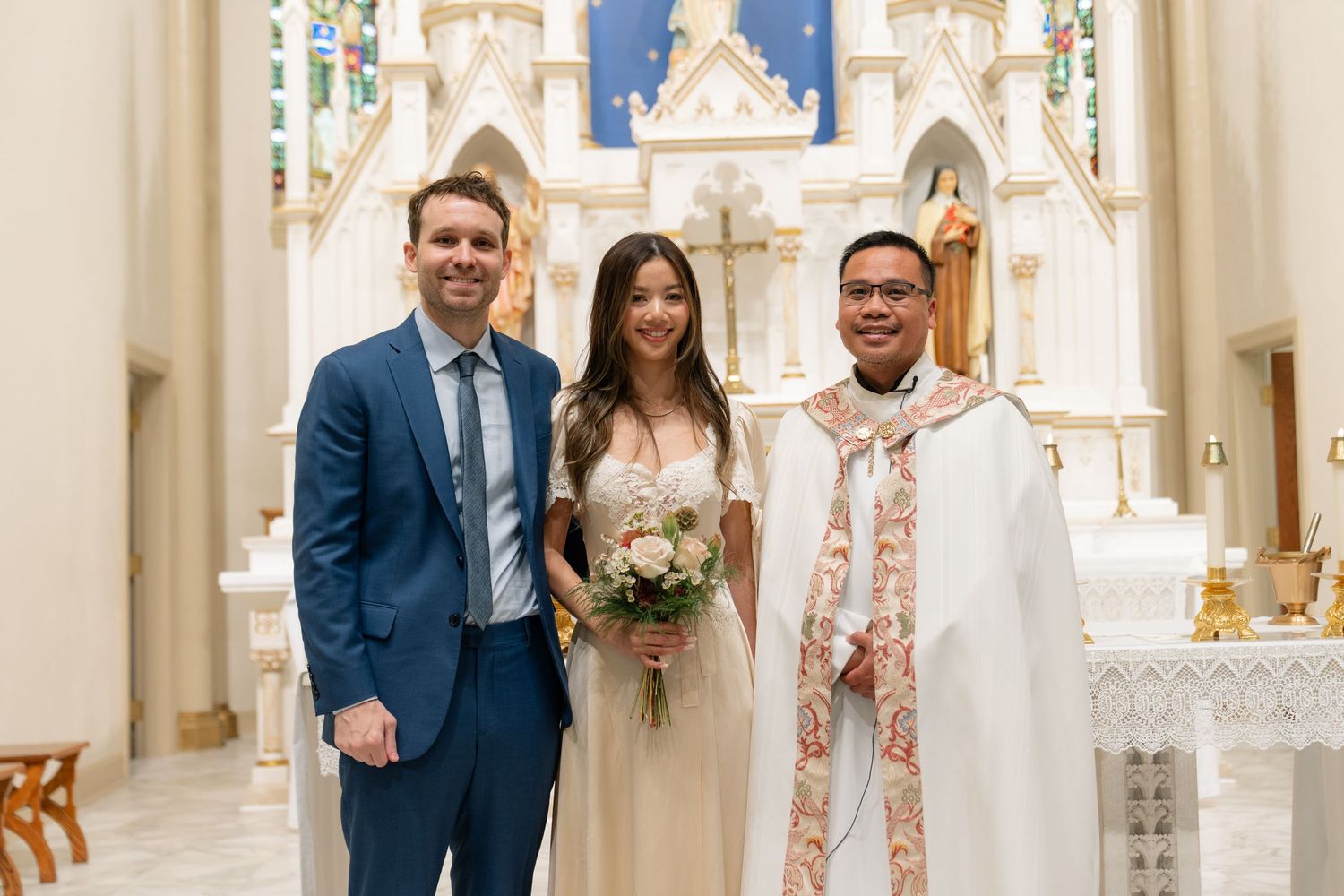 Elegant church interior with cream walls, ornate altar, and Gothic architectural details during a ceremony.