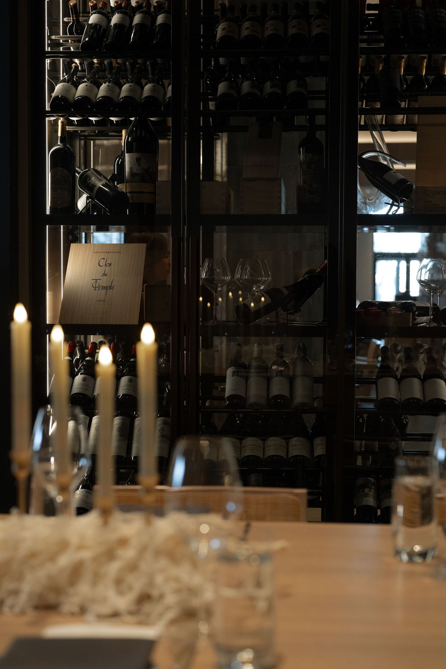An elegant dining setup with wine glasses and candles in a dimly lit restaurant interior.