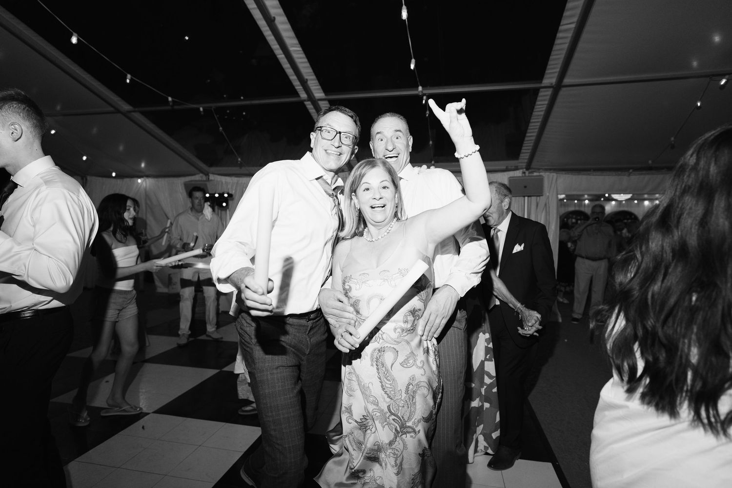 Black and white photo of guests dancing and celebrating at a wedding reception.