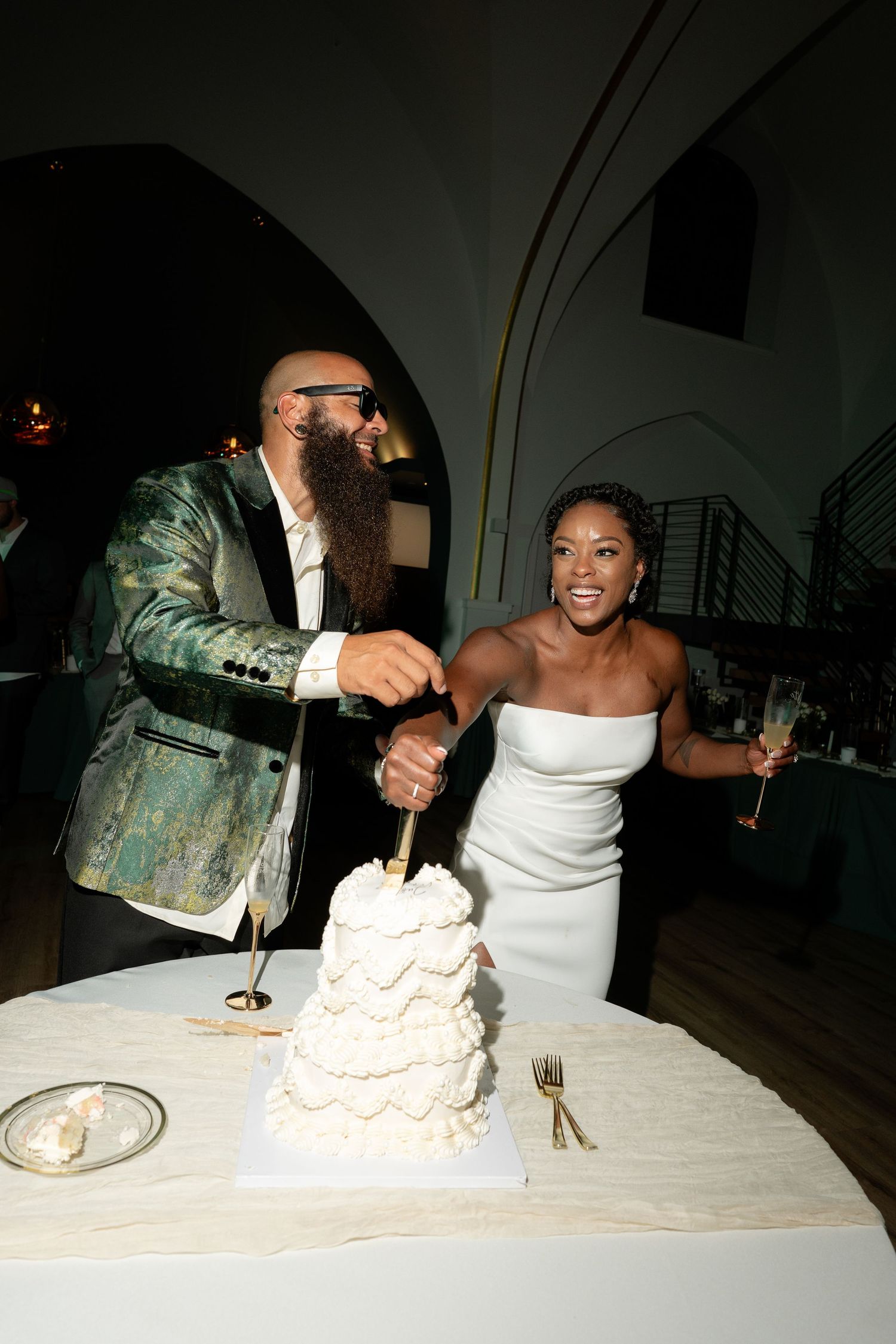 Couple sharing a joyful moment while cutting their wedding cake at the reception.