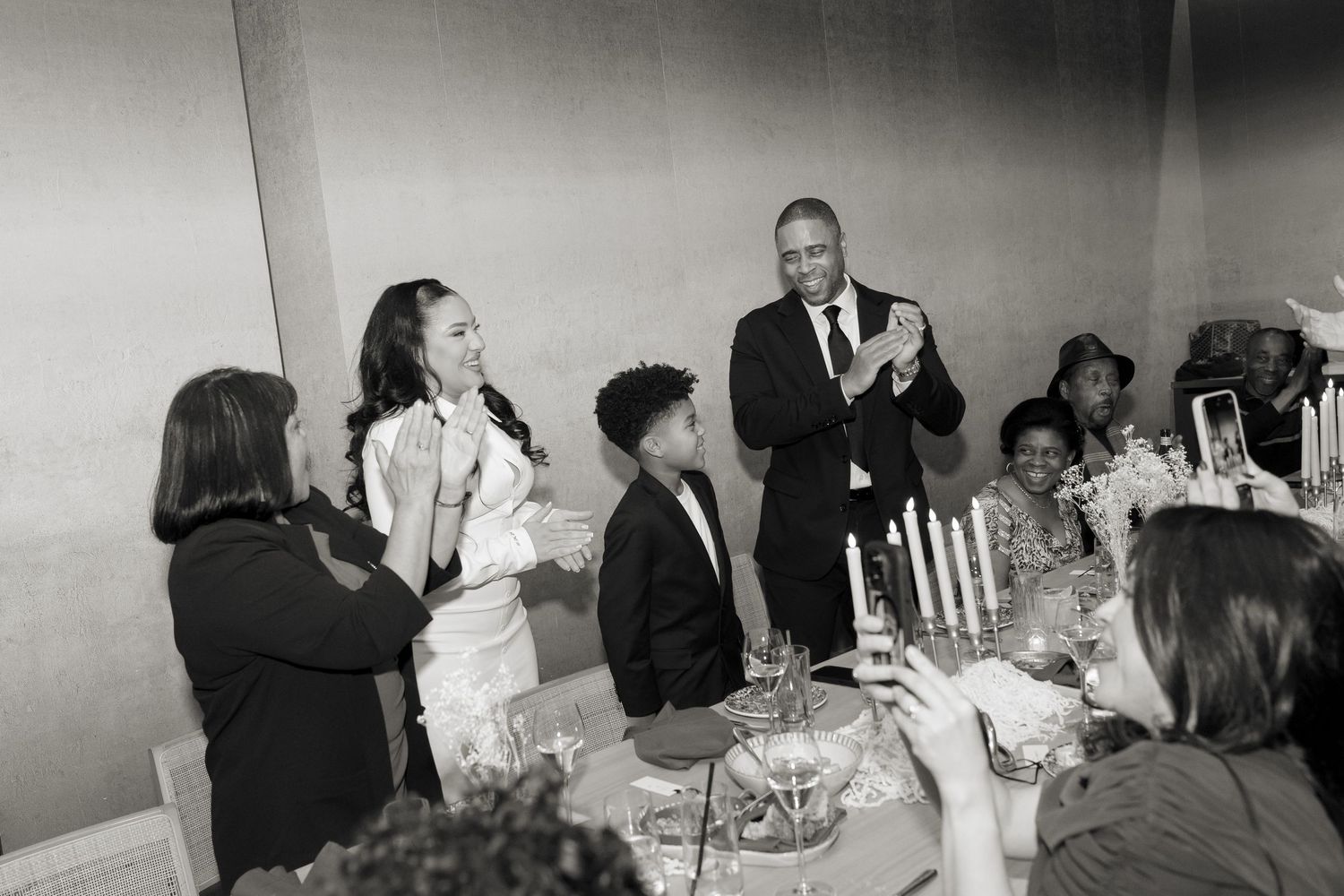Guests enjoying a formal dinner event in a bright room with candlelit tables.