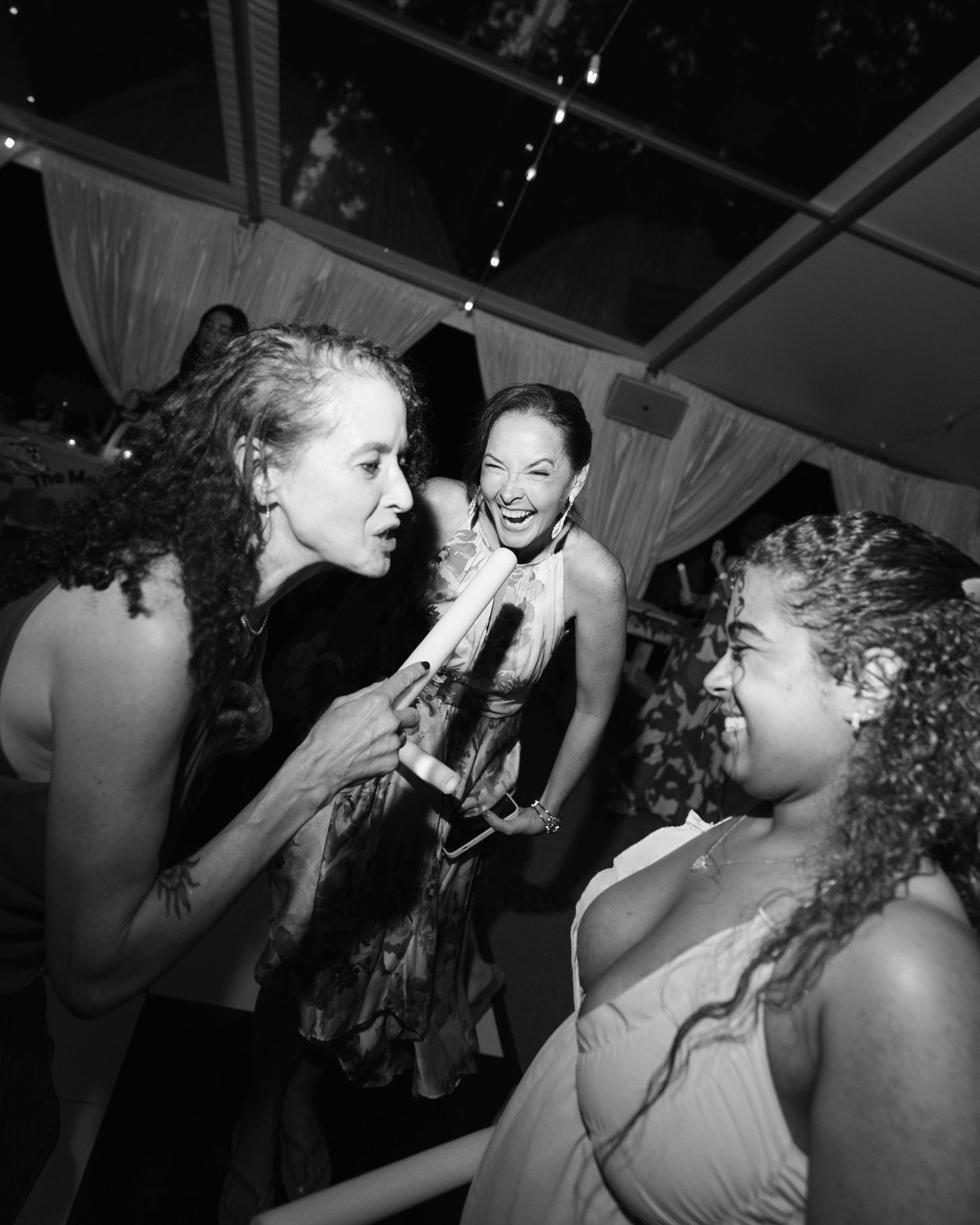 Black and white photo of guests laughing and celebrating at a wedding reception.