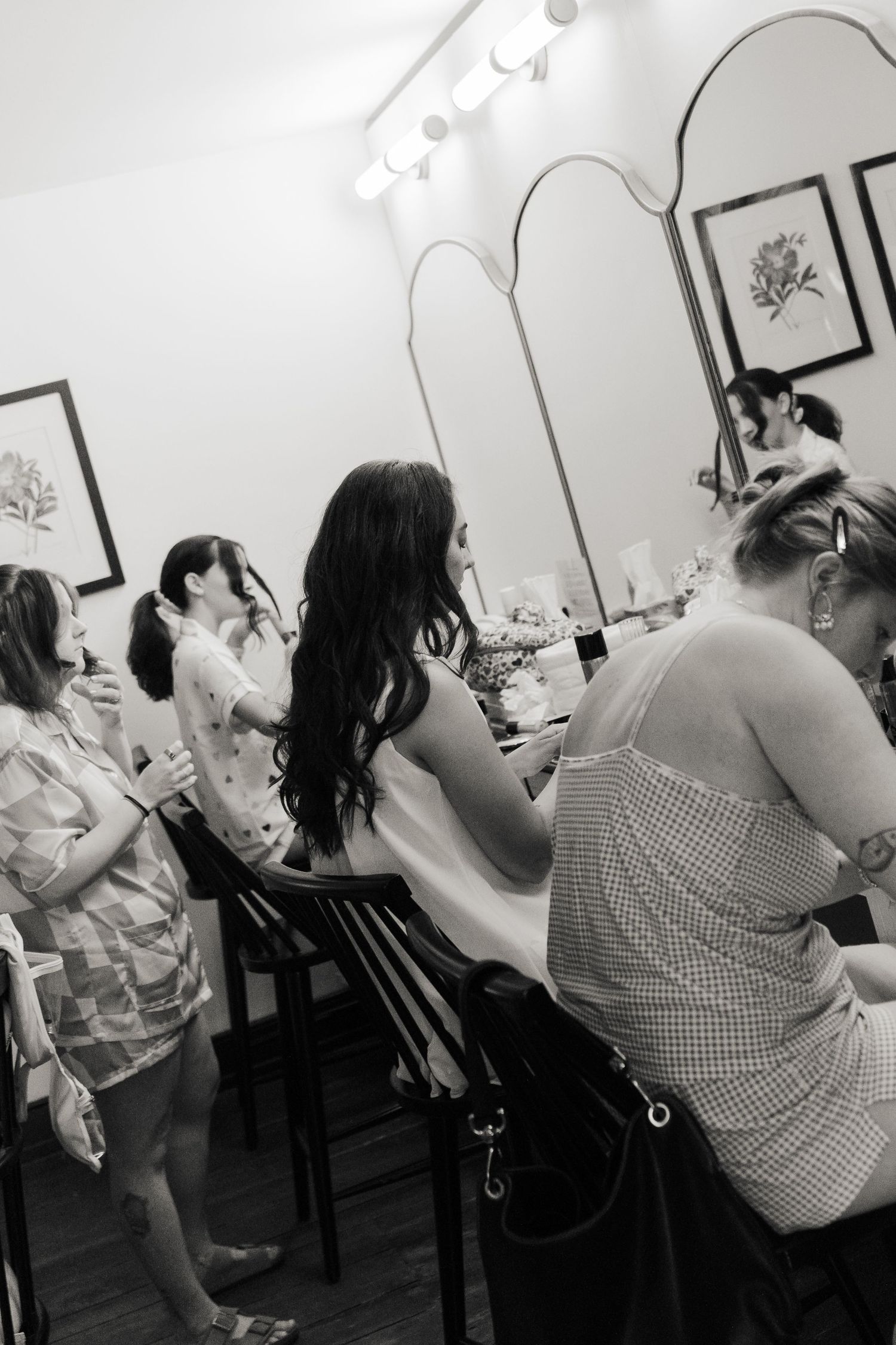 Black and white photo series showing wedding preparation activities in a salon mirror.