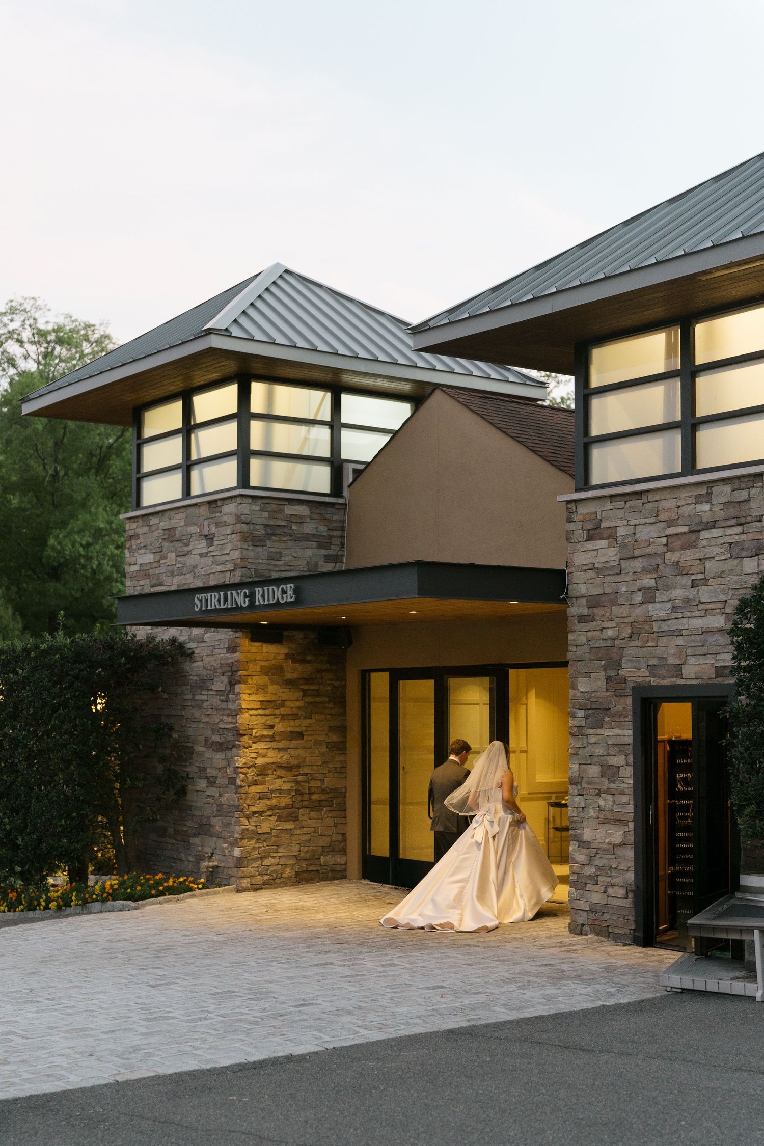 Bride and groom share romantic moment at entrance of Stirling Ridge wedding venue at dusk.