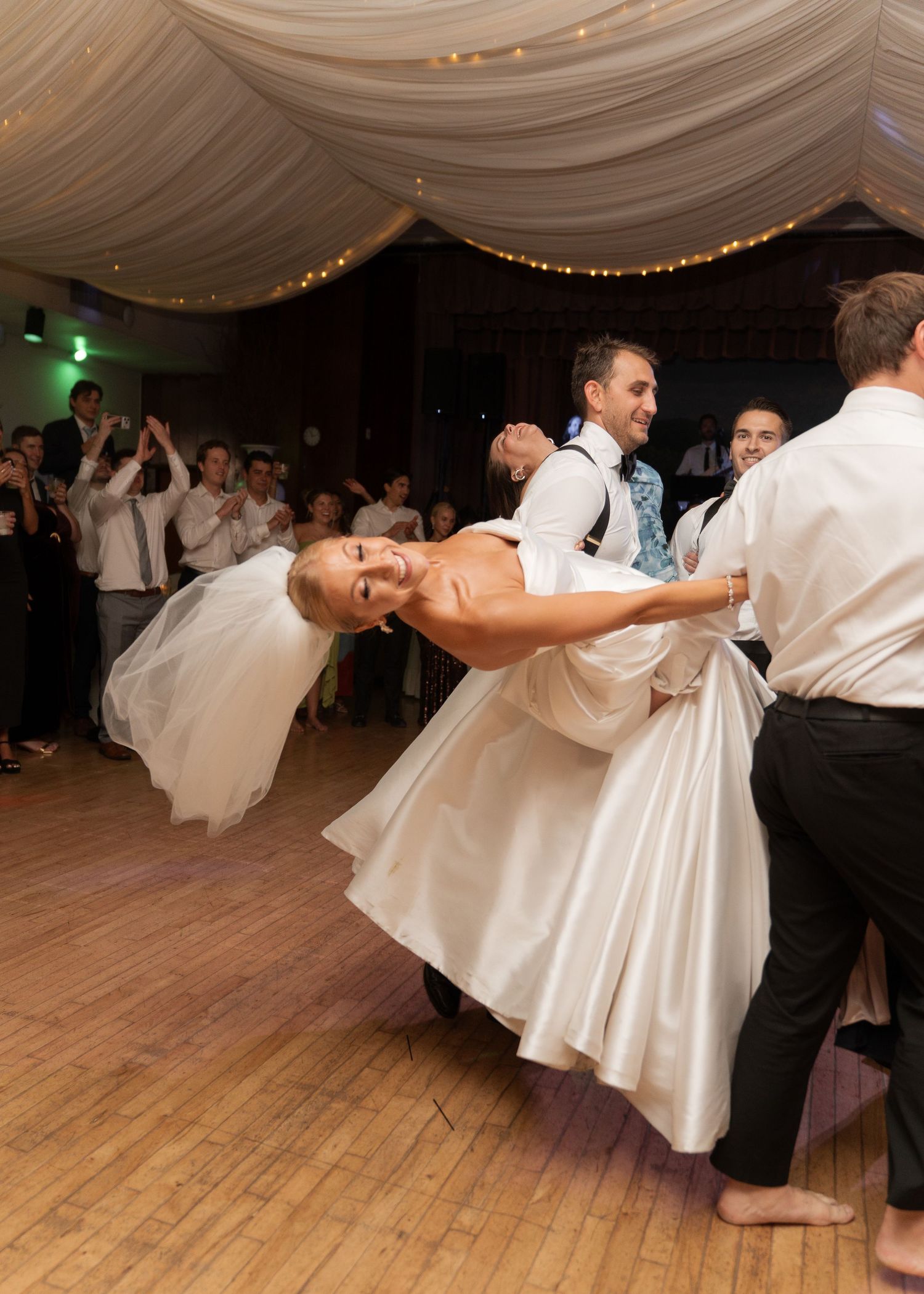 Groom dips bride dramatically on the dance floor during lively wedding reception celebration.