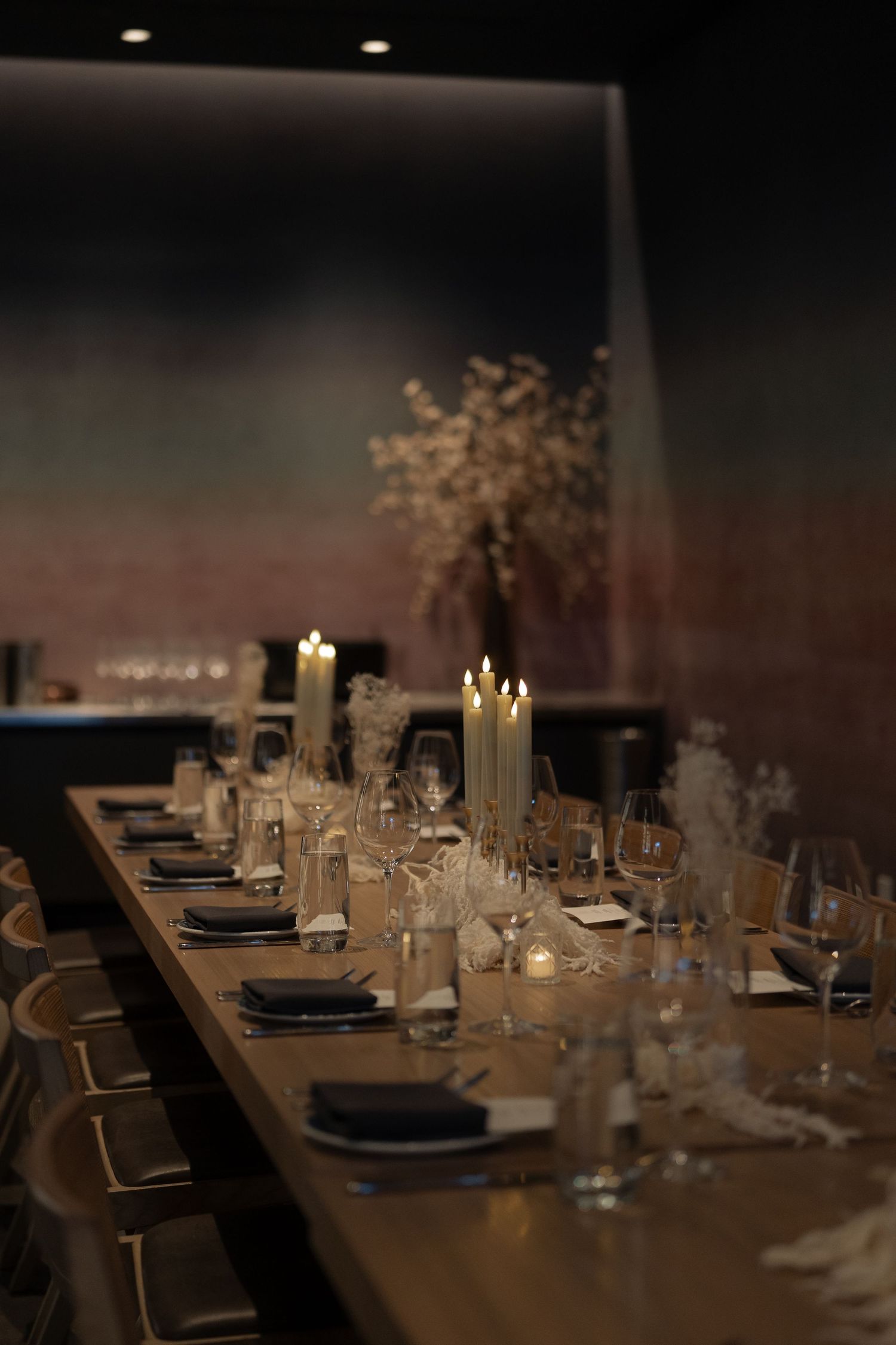 An elegant dining table set for a wedding reception with candles and delicate floral arrangements.