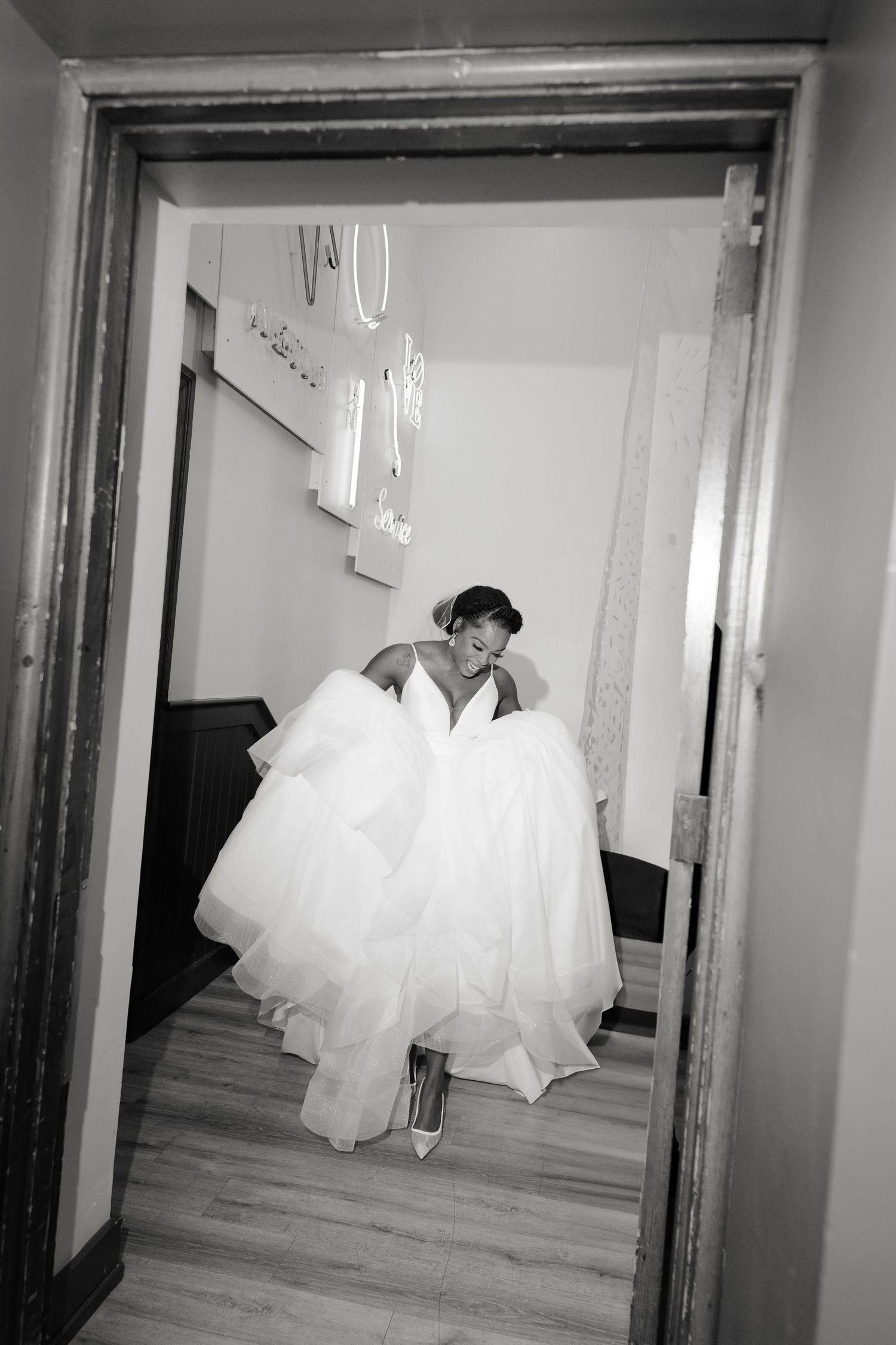 Wedding dress hanging in doorway creating dramatic silhouette in black and white photography.