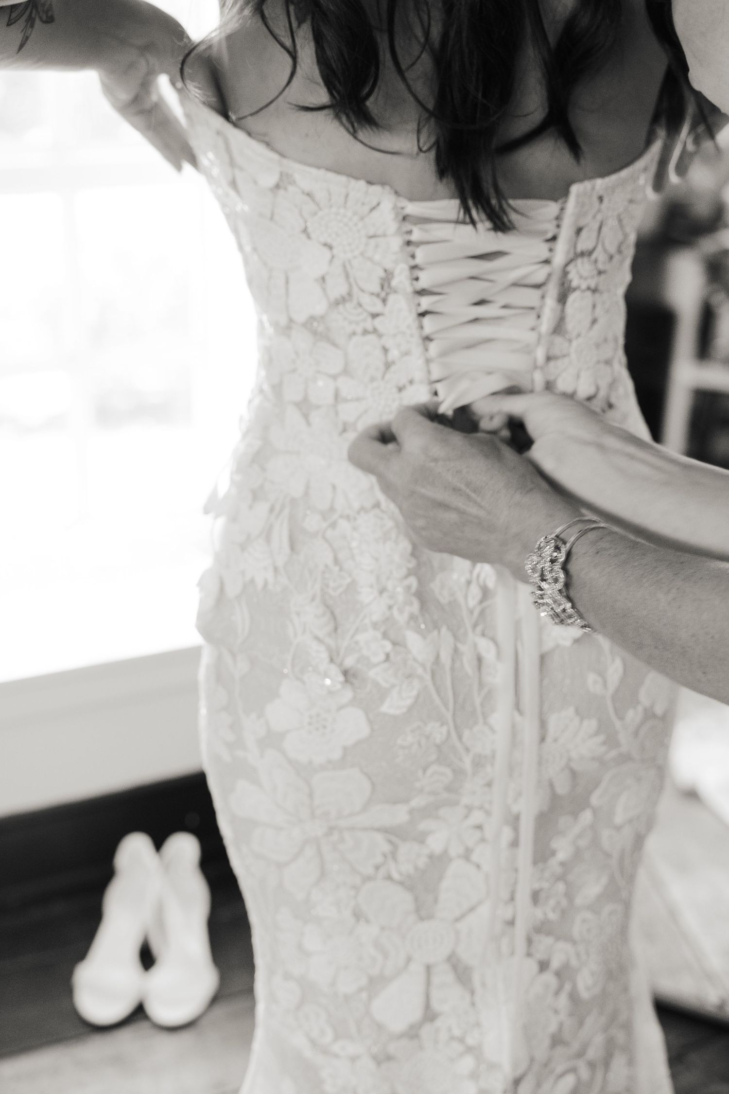 Close-up details of delicate white lace on a wedding dress with intricate floral patterns.