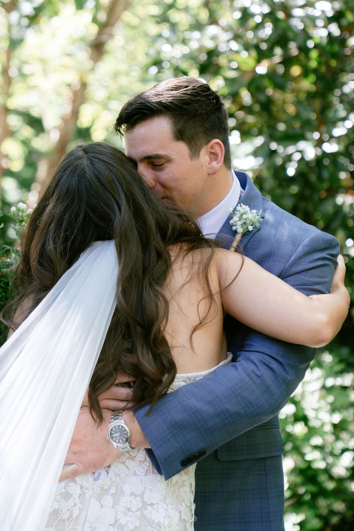 A romantic first kiss moment between newlyweds in a garden setting.