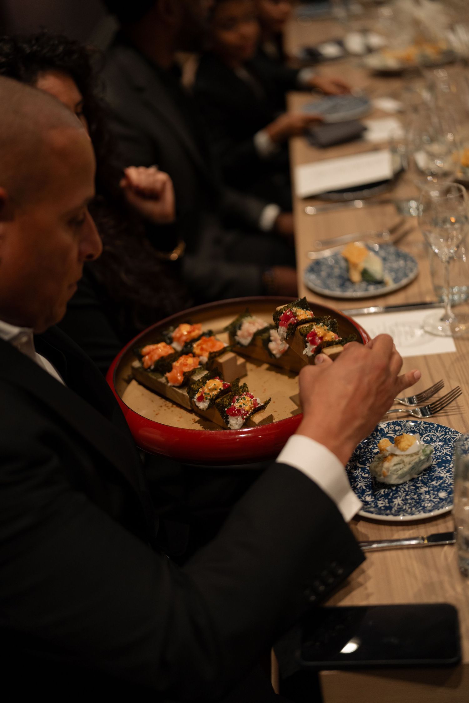 Elegant dinner plates with colorful food being served at a formal event.