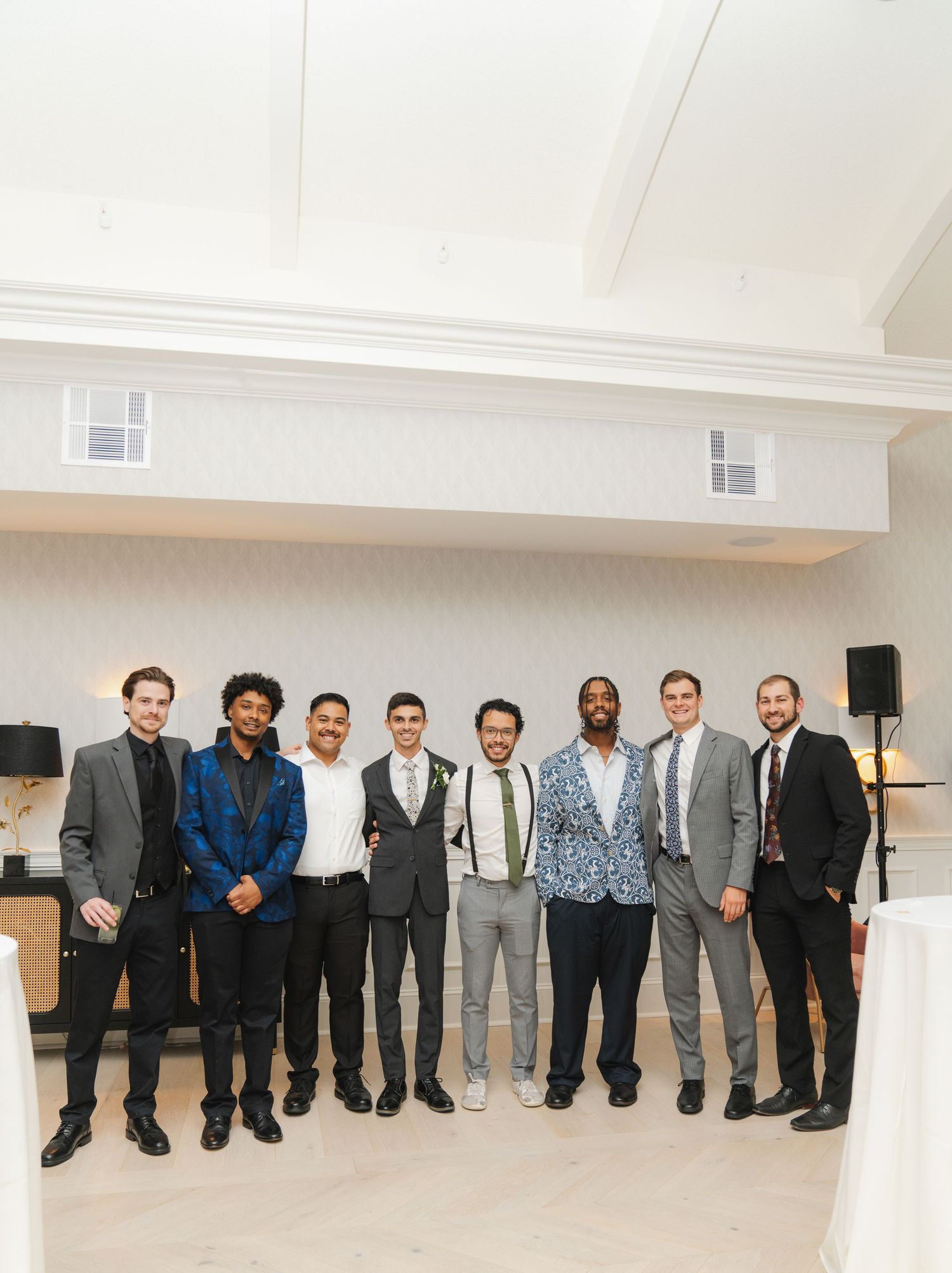 A panoramic group photo of people in formal business attire standing together in a bright white room.