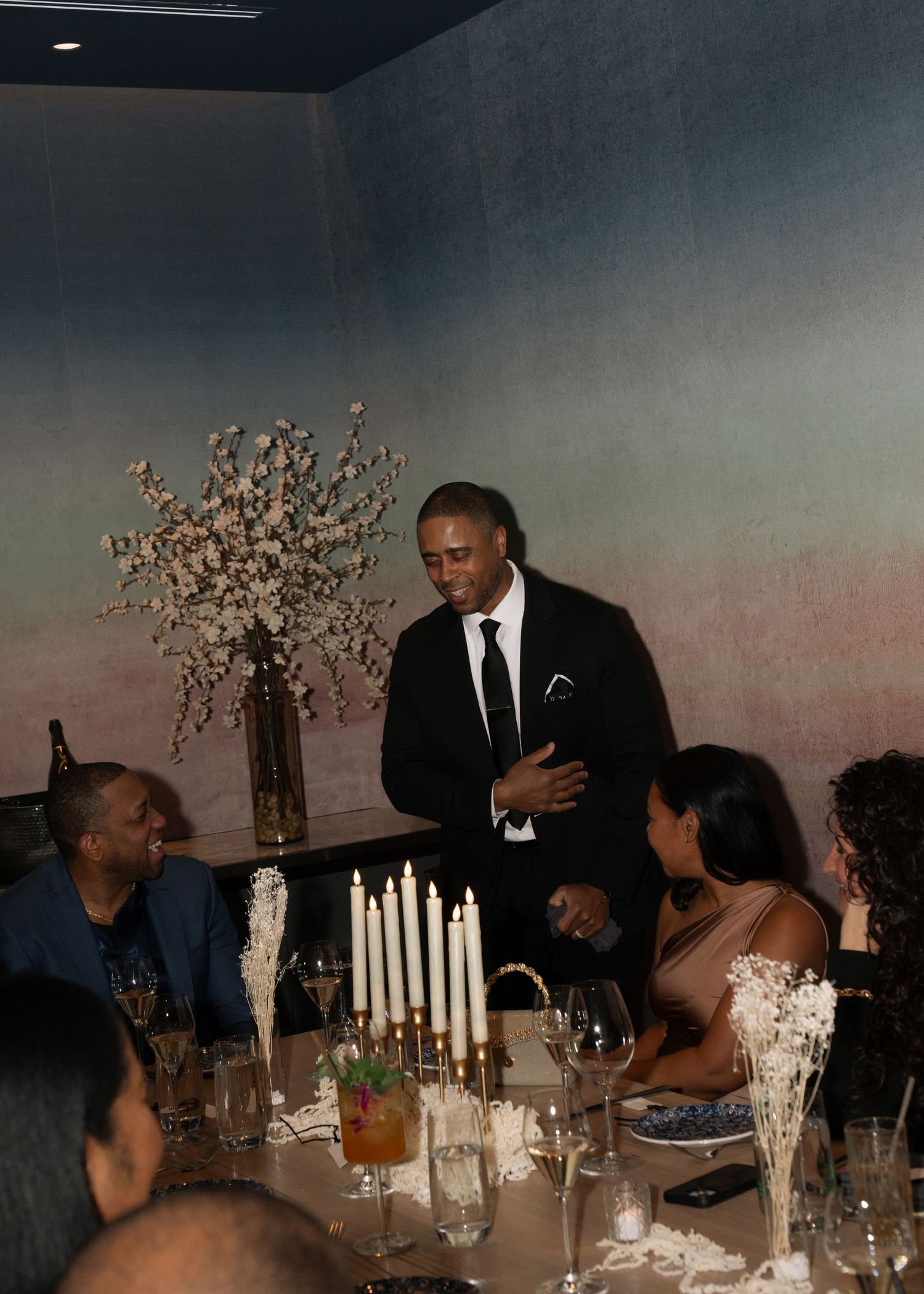 Wedding reception tables decorated with tall candles and floral centerpieces in an elegant dining room.