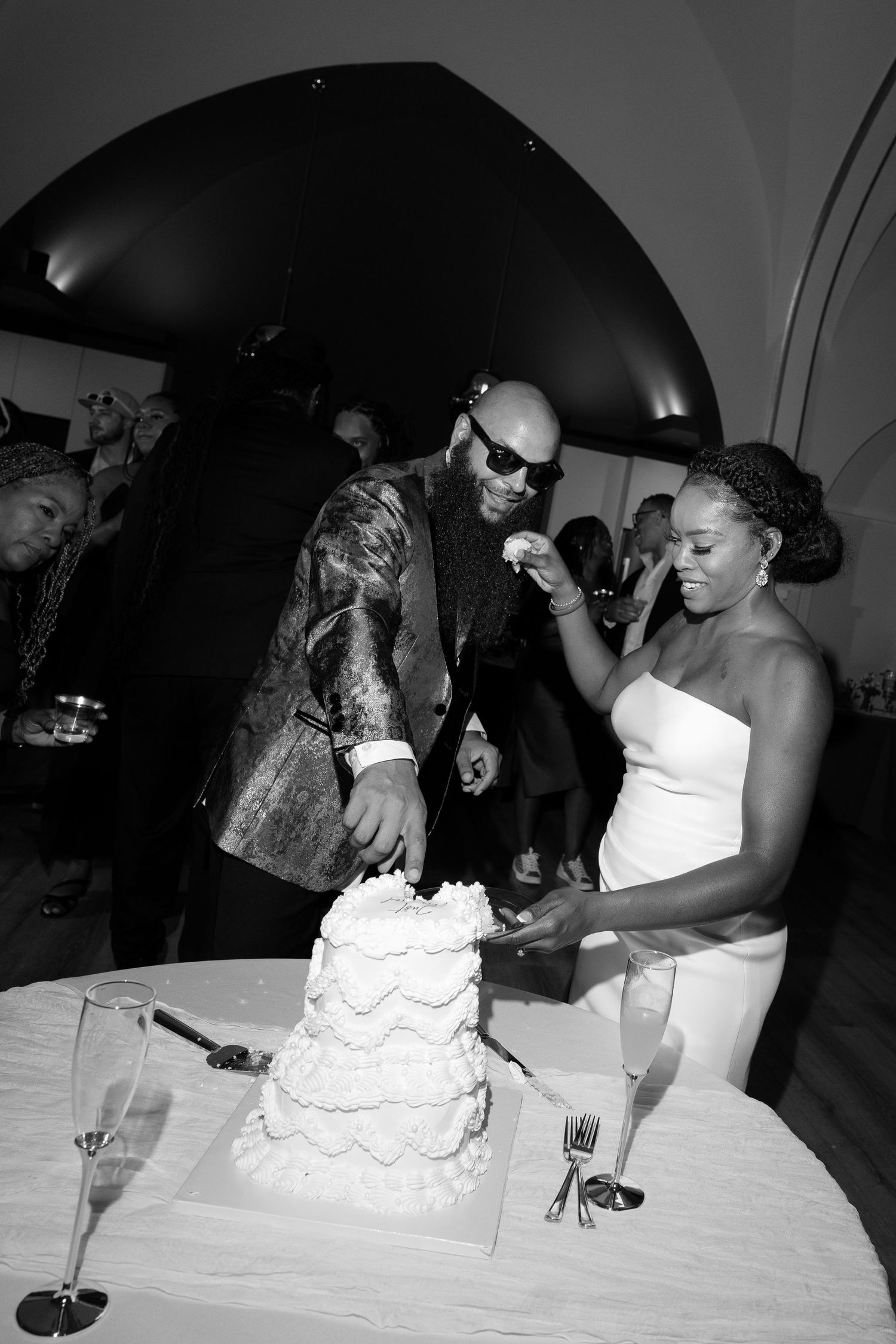 Black and white photo of wedding cake cutting ceremony at reception.