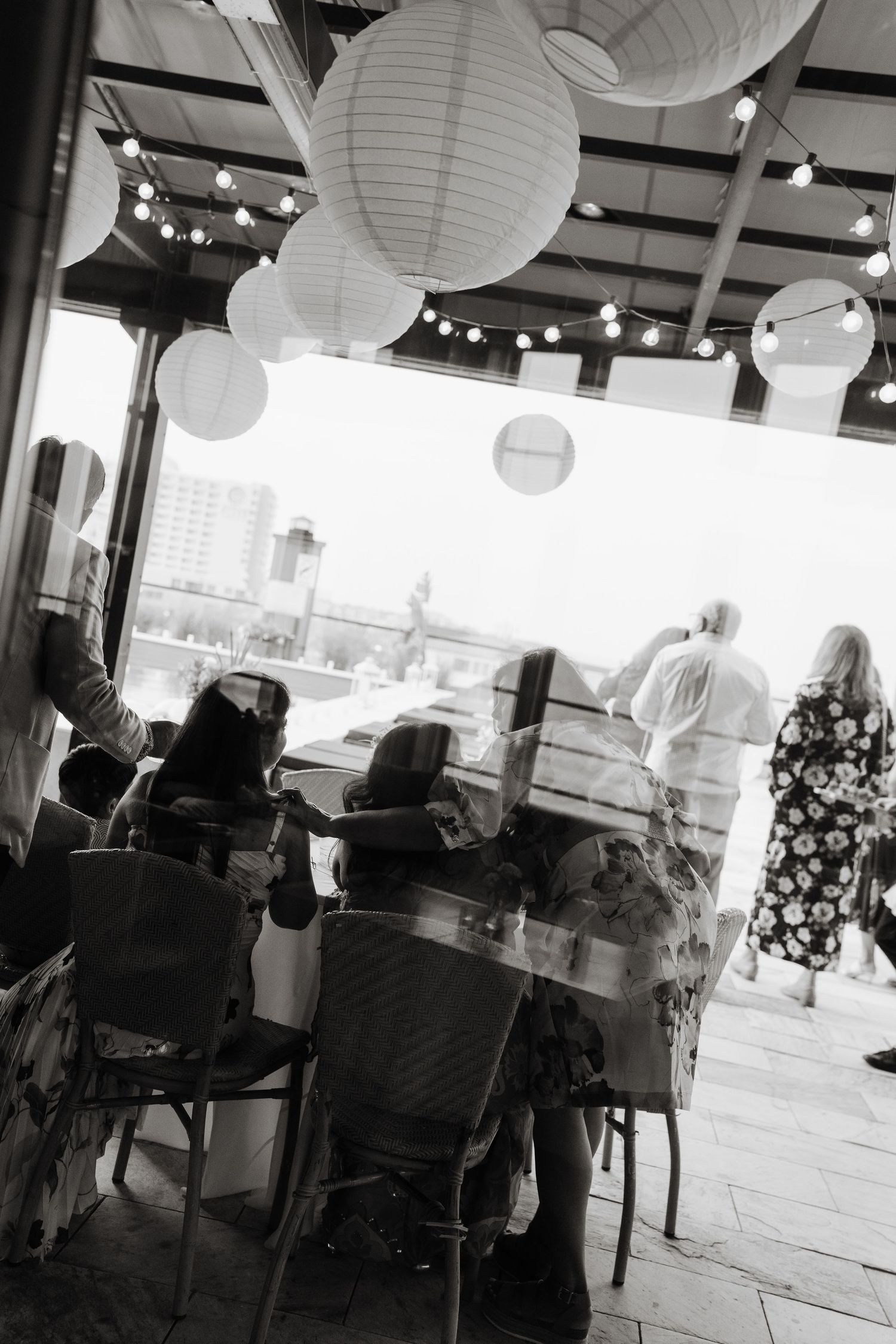 Modern event space with white paper lanterns hanging from ceiling and guests seated at tables.