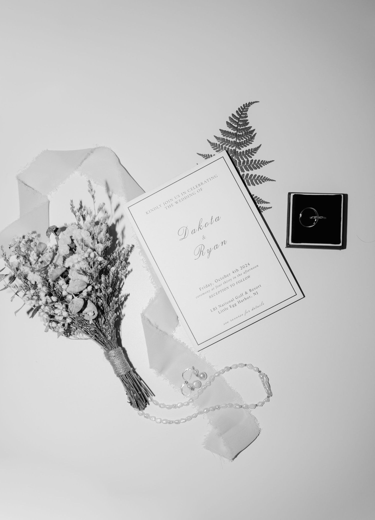 Black and white photographs of dried flower bouquets with elegant place cards and ferns arranged in a minimalist style.