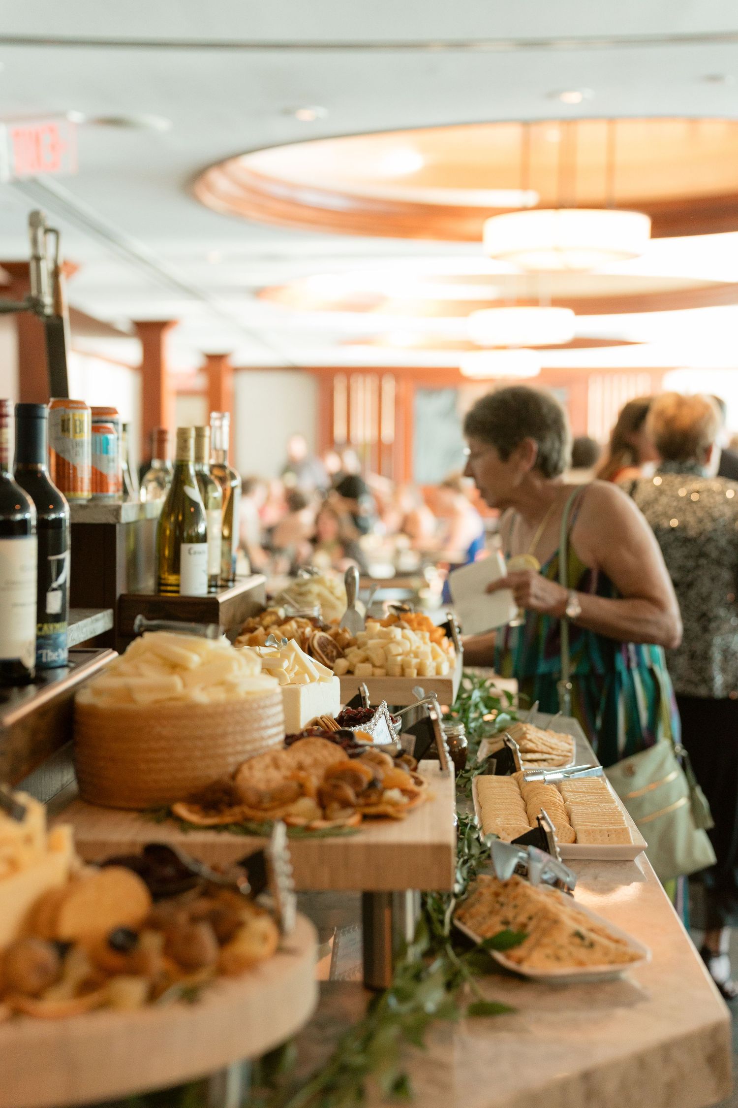 Elegant wedding reception cocktail hour featuring a charcuterie and cheese board spread with wine bottles and guests mingling.