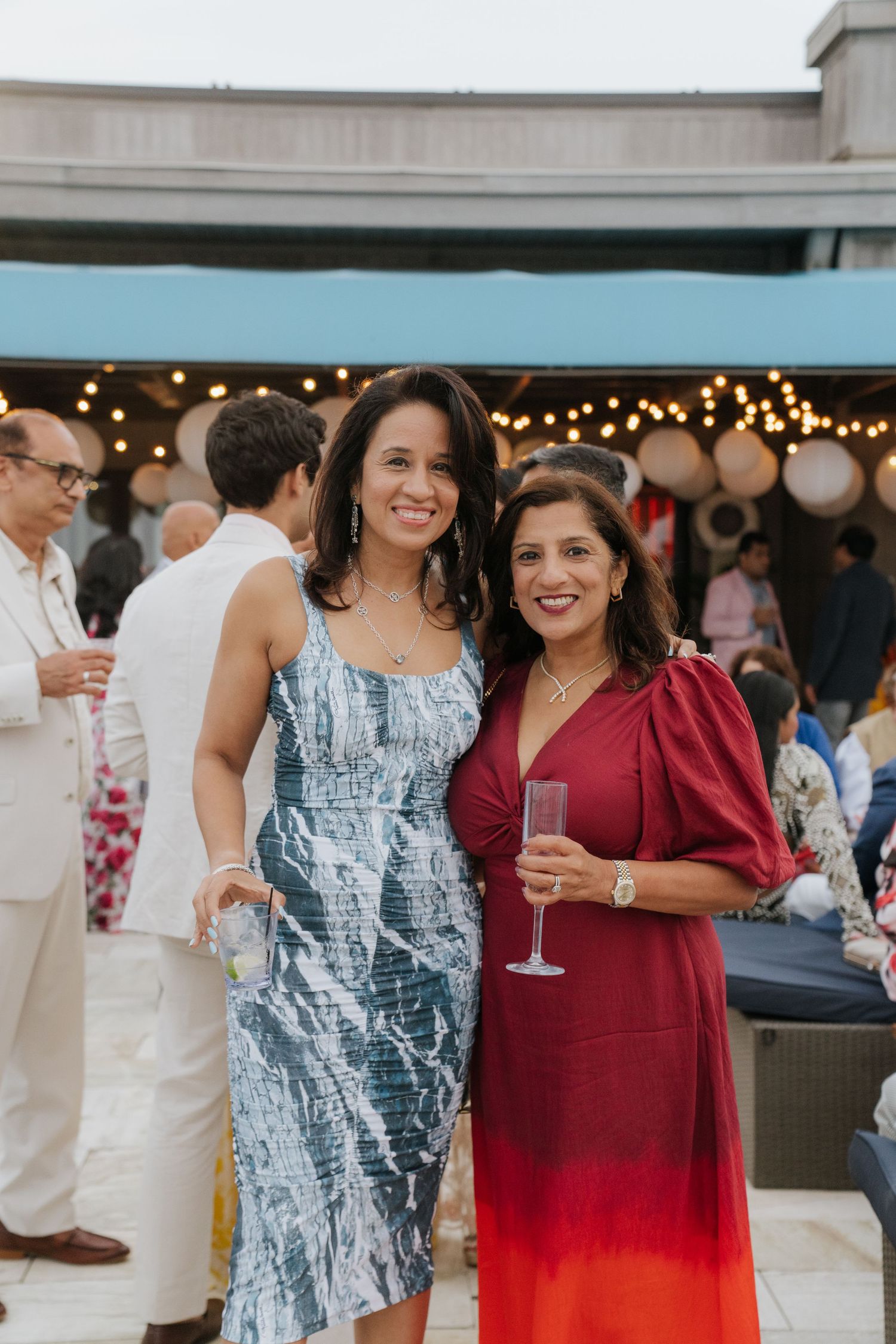 Guests enjoying drinks at an outdoor party with string lights and festive atmosphere.