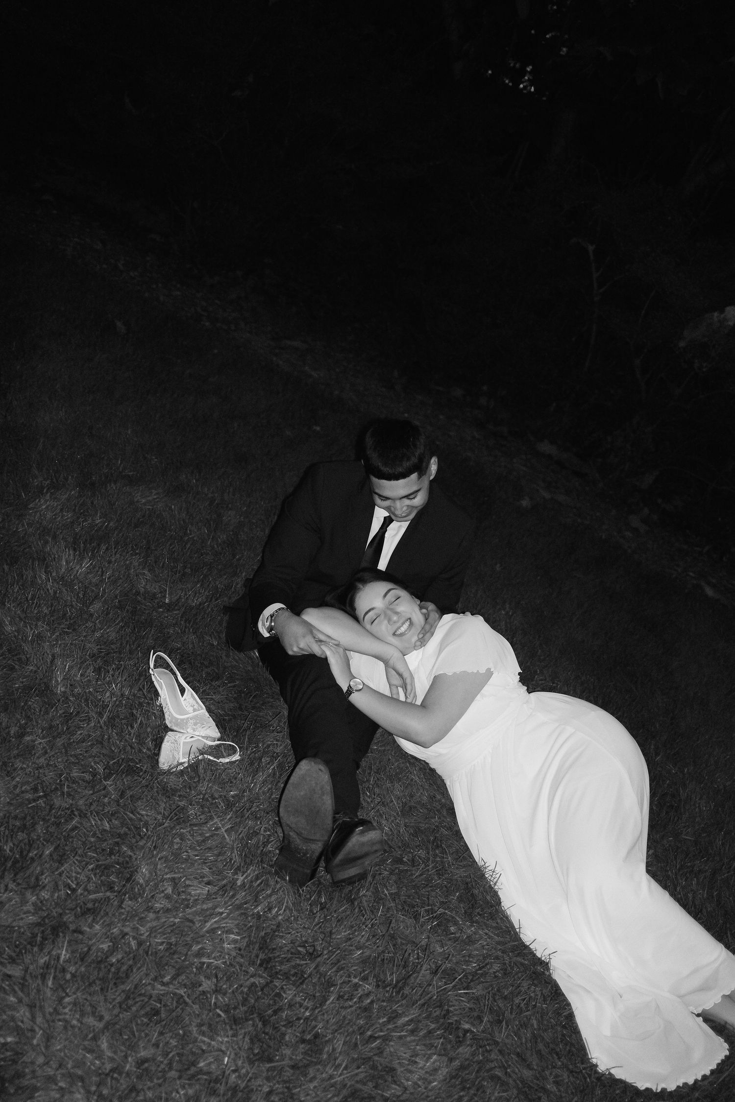 A couple lies in the grass at night during their wedding photoshoot.