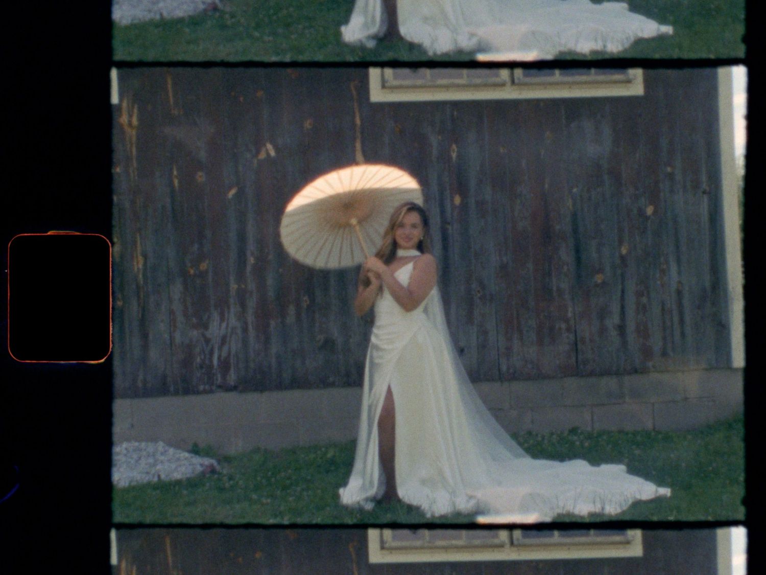 Bride in elegant white gown holding parasol umbrella outdoors in vintage film strip style photo.
