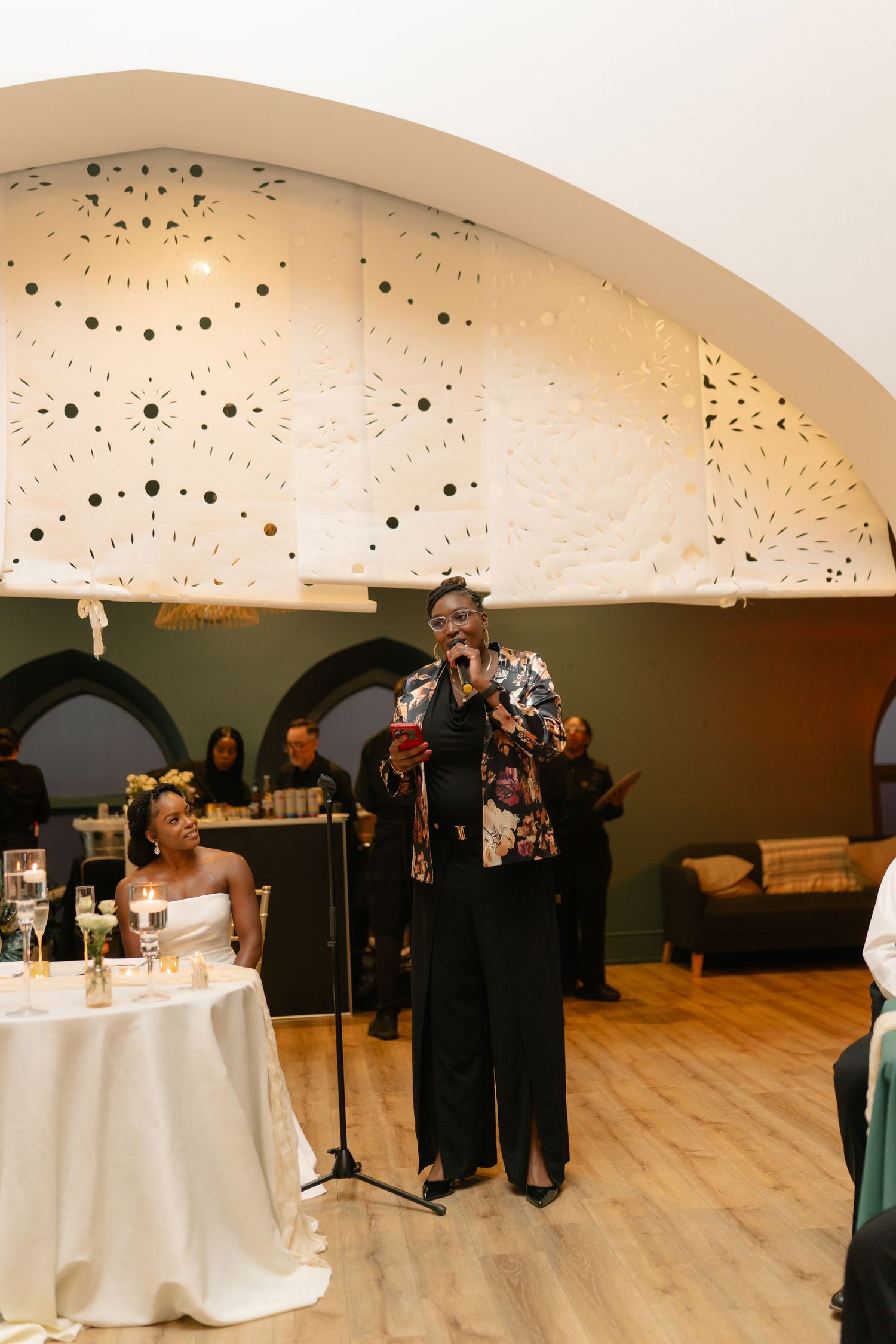 An elegant reception venue with arched ceilings, hardwood floors and white-clothed tables.