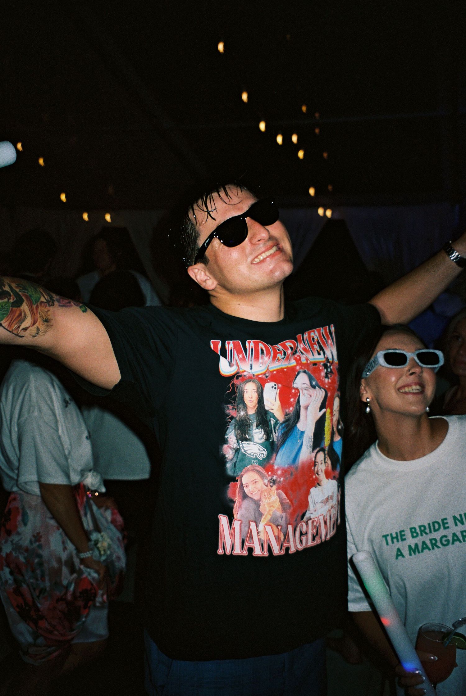 Wedding reception dance party with guests wearing graphic t-shirts and sunglasses.