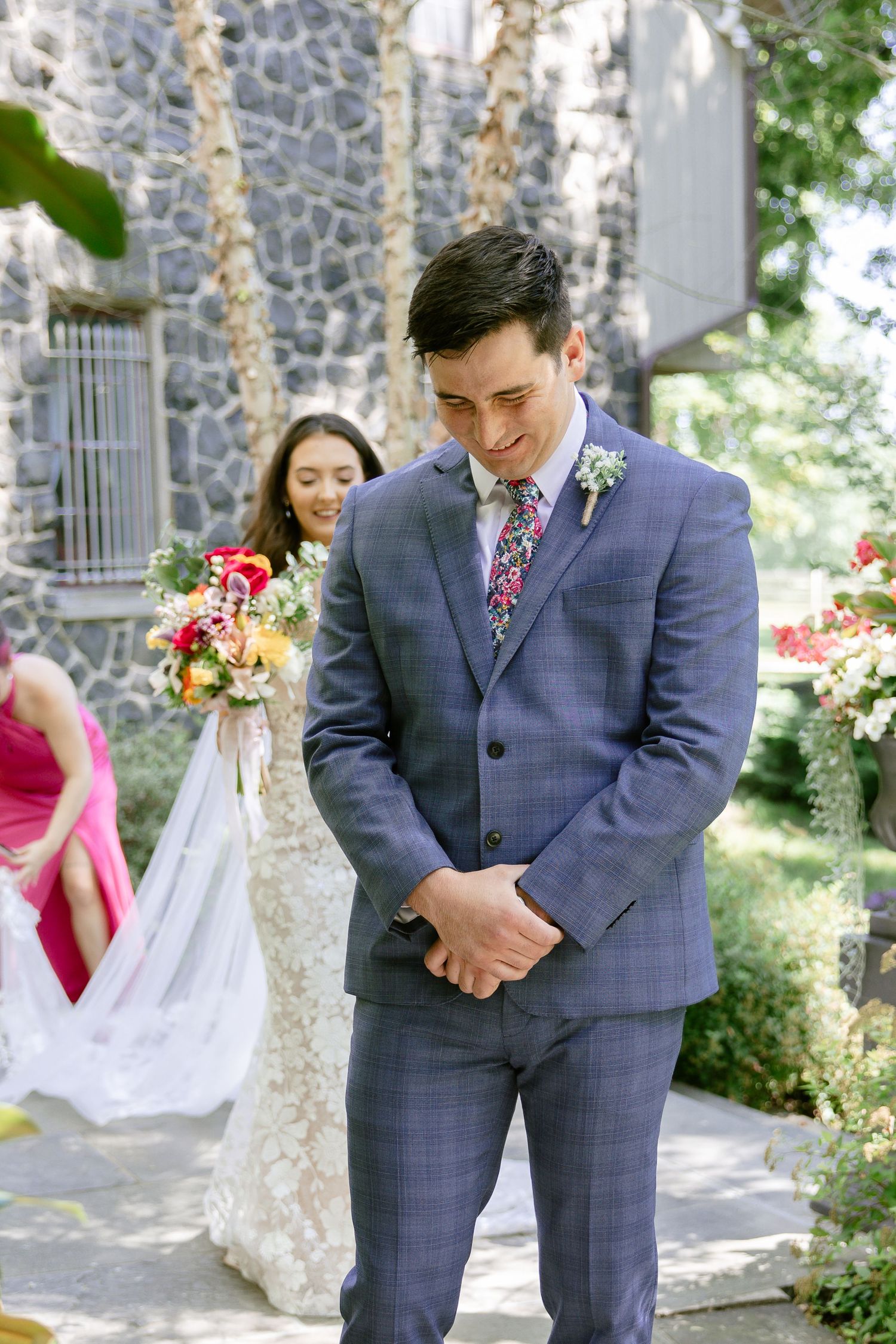 Wedding party poses outside a stone church building with floral decorations.