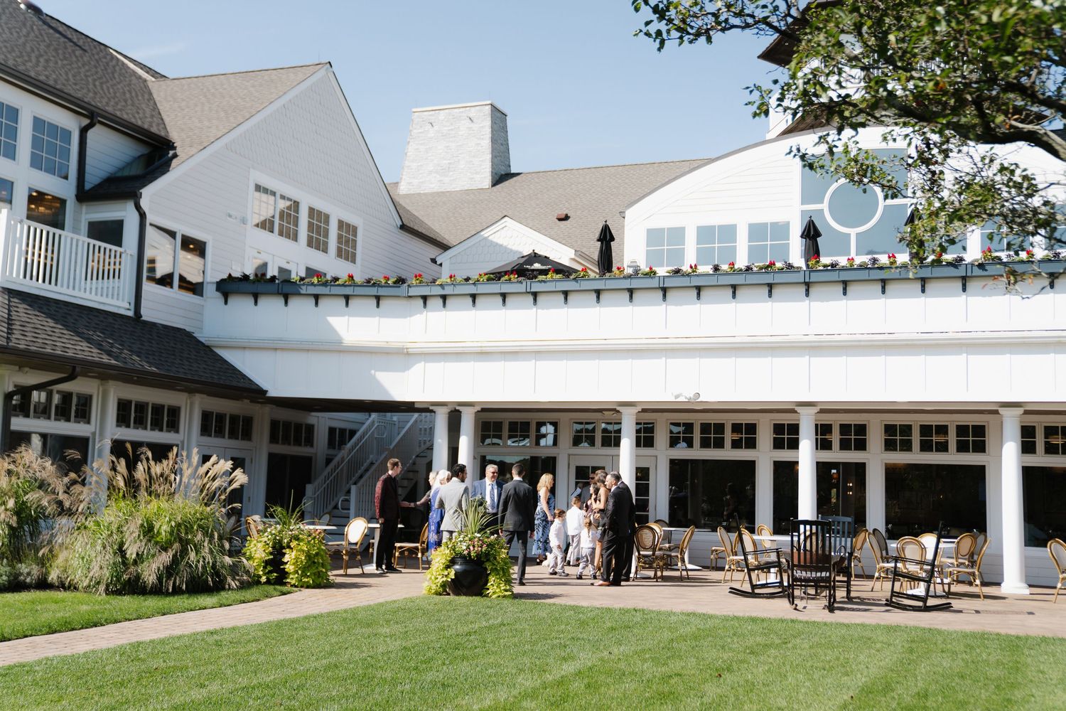 A panoramic view of a white modern building exterior with columns and covered walkways surrounded by landscaping.