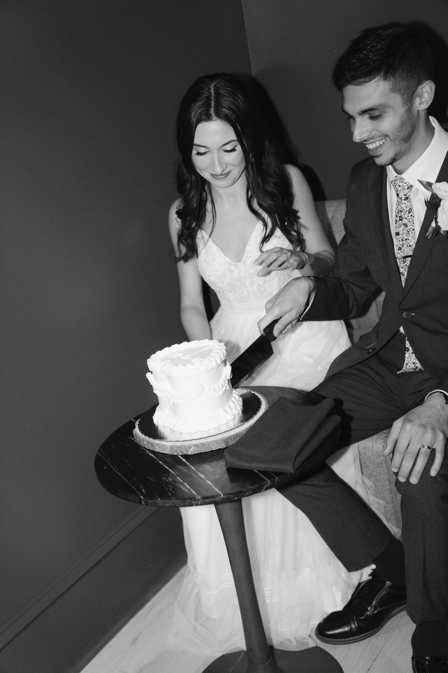 Black and white wedding photo sequence shows couple playfully smashing cake into each other's faces during reception.