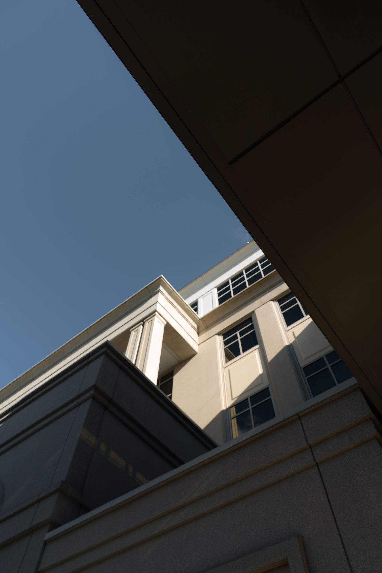 Low angle architectural shot of a modern white building against blue sky.