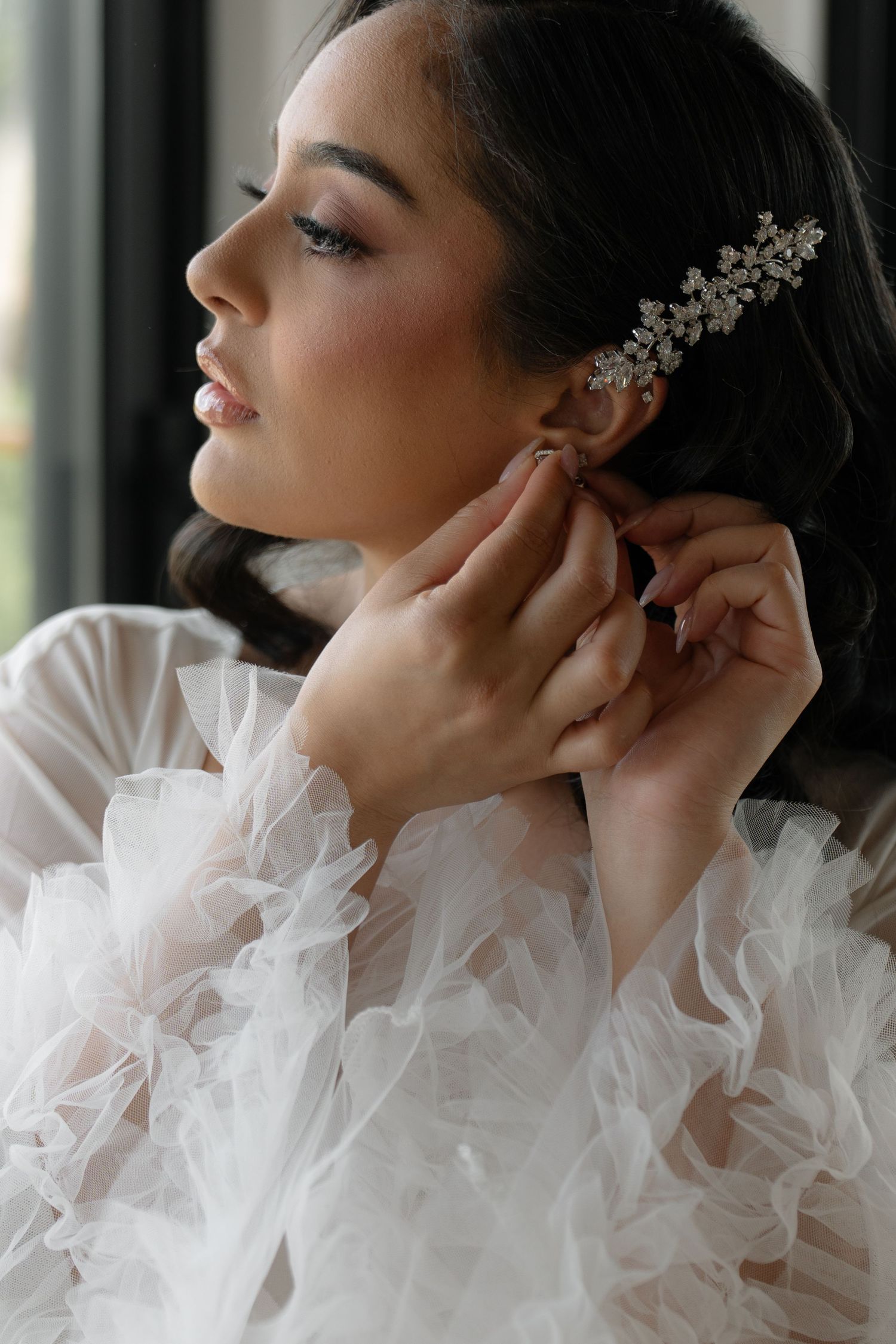 Close-up profile shot showing delicate bridal jewelry and tulle details.